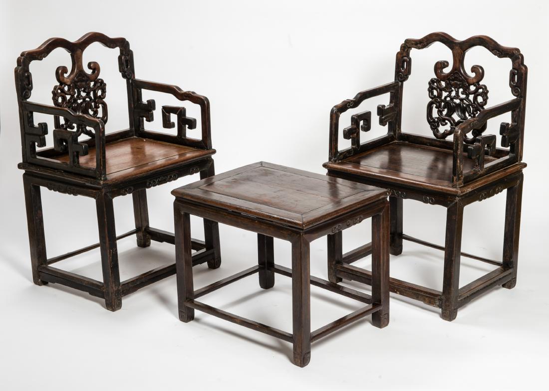 TWO CHAIRS AND A SMALL TABLE: TWO CHAIRS AND A SMALL TABLE Fine dark wood China, Qing dynasty (1644 - 1912) Two chairs with decoratively formed, open-work backrest, the upper edge of which has an elegant curve. Likewise, the sides