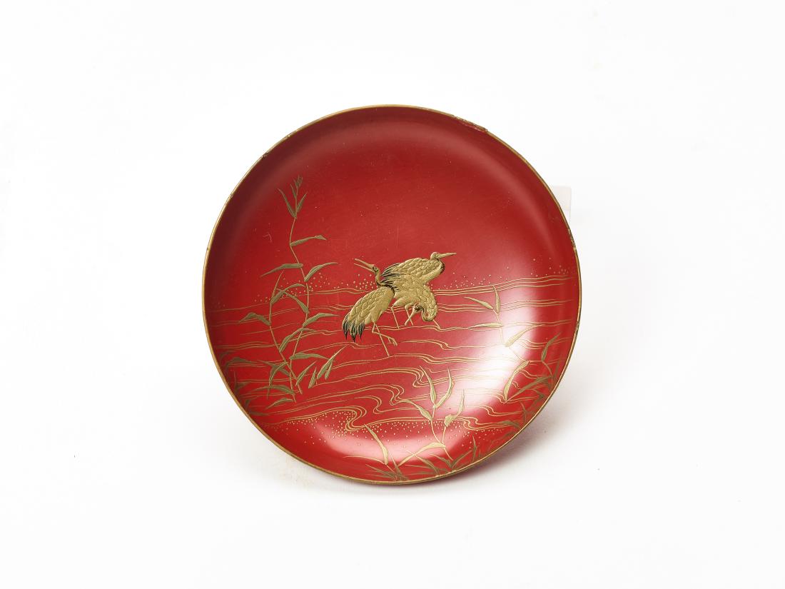 A SMALL LACQUERED SAKAZUKI (SAKE CUP) WITH CRANES: A SMALL LACQUERED SAKAZUKI (SAKE CUP) WITH CRANES Lacquered wood Japan, Meiji period The flat saucer-like footed sake cup is covered in red lacquer with gold takamaki-e and hiramaki-e depicting three 