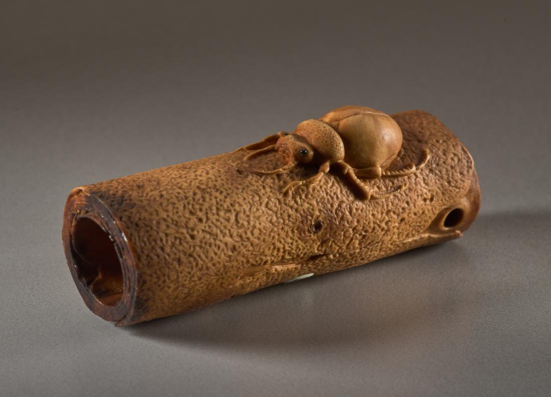 A BOXWOOD NETSUKE BY DERKACHENKO OF A BEETLE ON A TREE: A BOXWOOD NETSUKE BY DERKACHENKO OF A BEETLE ON A TREE TRUNK Boxwood netsuke Ukraine, contemporary A naturalistic, precisely carved beetle with black inlaid eyes on a hollow piece of a tree trunk. The