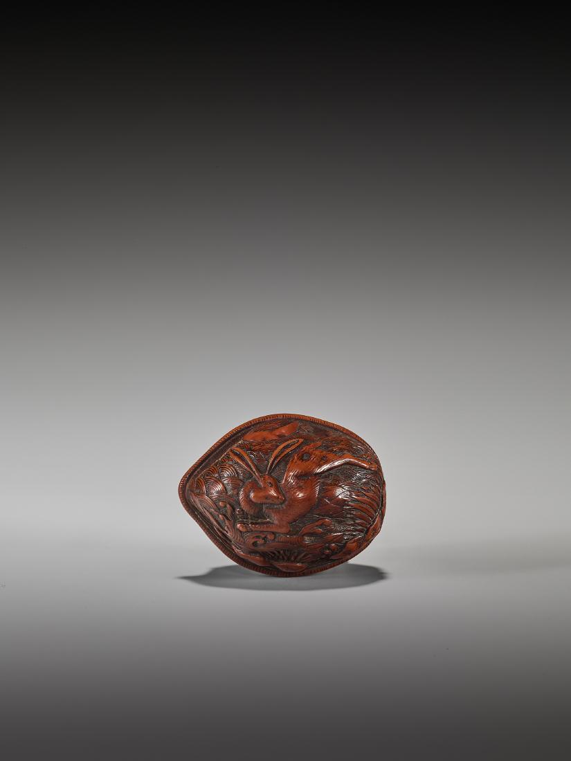 A RARE WALNUT NETSUKE OF A LUNAR HARE: A RARE WALNUT NETSUKE OF A LUNAR HARE Unsigned, walnut netsuke Japan, 19th century, Edo period (1615-1868) Carving a whole nut in relief is quite an artistic feat due to its difficulty. The top side s
