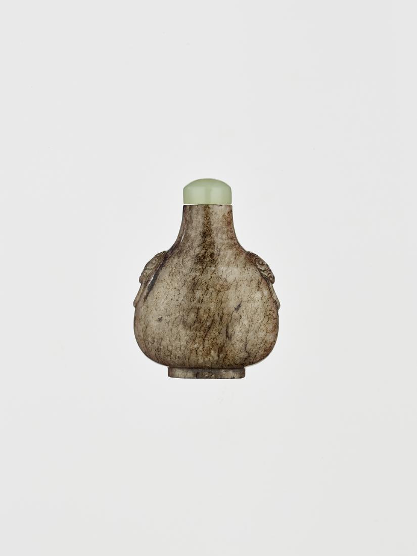 A JADE SNUFF BOTTLE, 18TH CENTURY: A JADE SNUFF BOTTLE, 18TH CENTURY The grey nephrite with dark brown and black veining. Well carved lion mask with handles to shoulders. Pear shape with raised oval foot rim. Superb hollowing and very 