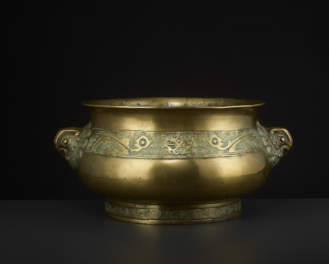A LARGE BRONZE CENSER, 1837: A LARGE BRONZE CENSER, 1837 The vessel in bombe-shape with well-cast phoenix masks to the shoulders. Inscribed Daoguang Ding You. The body with an incised archaistic scroll bearing taotie and stylized