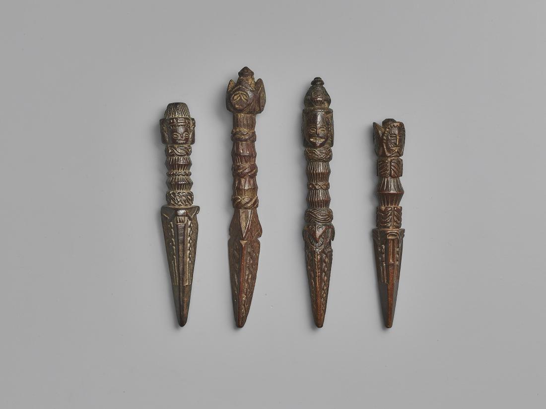 FOUR NEPALESE CARVED WOOD PHURBUS: FOUR NEPALESE CARVED WOOD PHURBUS Nepal, 17th-19th century. This lot comprises four phurbus, each with a handle showing multiple abstracted human faces. Geometrical decoration adorns the entire surfac