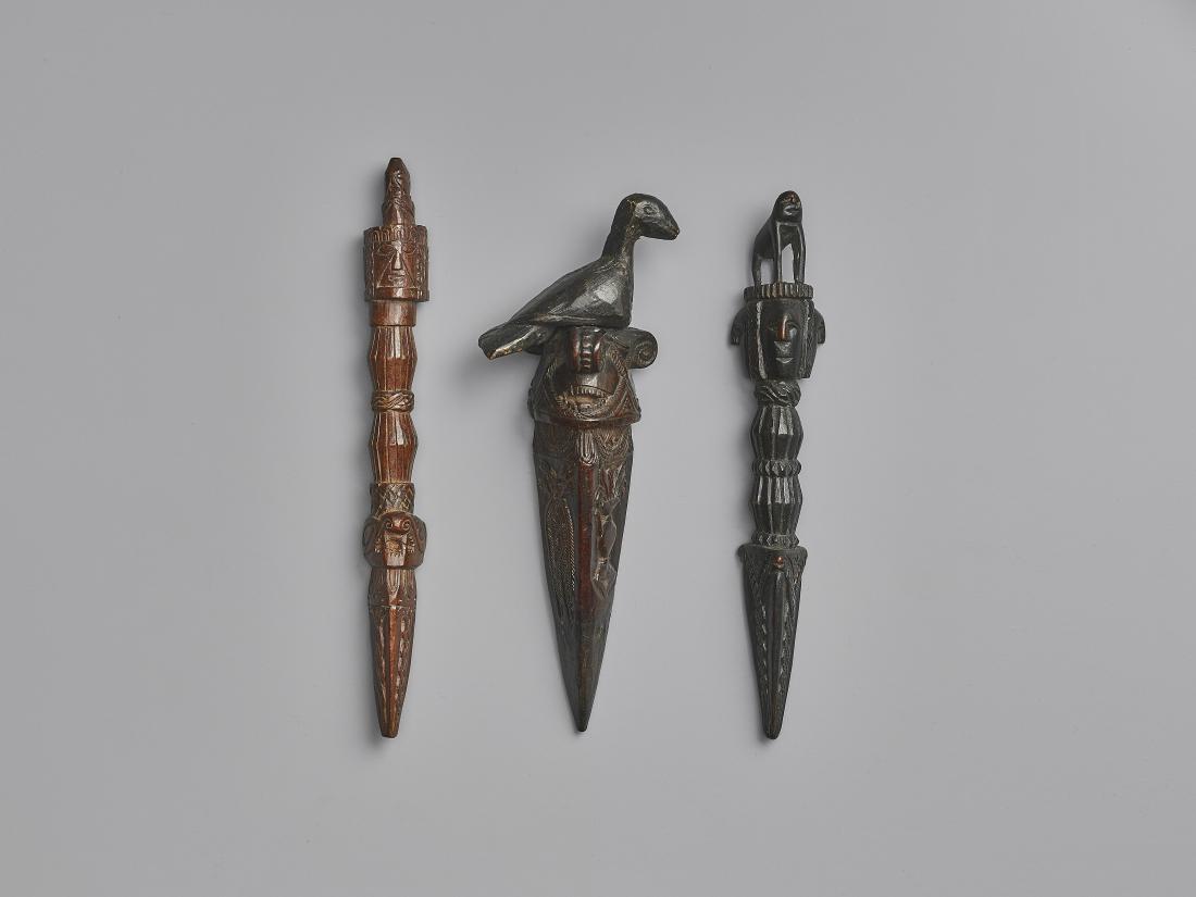 THREE NEPALESE CARVED WOOD PHURBUS: THREE NEPALESE CARVED WOOD PHURBUS Nepal, 17th-19th century. This lot comprises three phurbus, two with an animal finial. Geometrical decora-tion adorns the entire surfaces and include tridents, inter