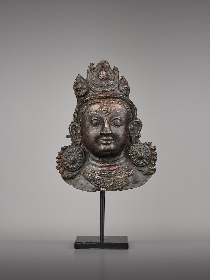 A COPPER REPOUSSE MASK OF BHAIRAVA: A COPPER REPOUSSE MASK OF BHAIRAVA Nepal, 17th century. The expressive copper mask with well-executed incision and embossing work. Modern stand. (2) Provenance: A German collector. Condition