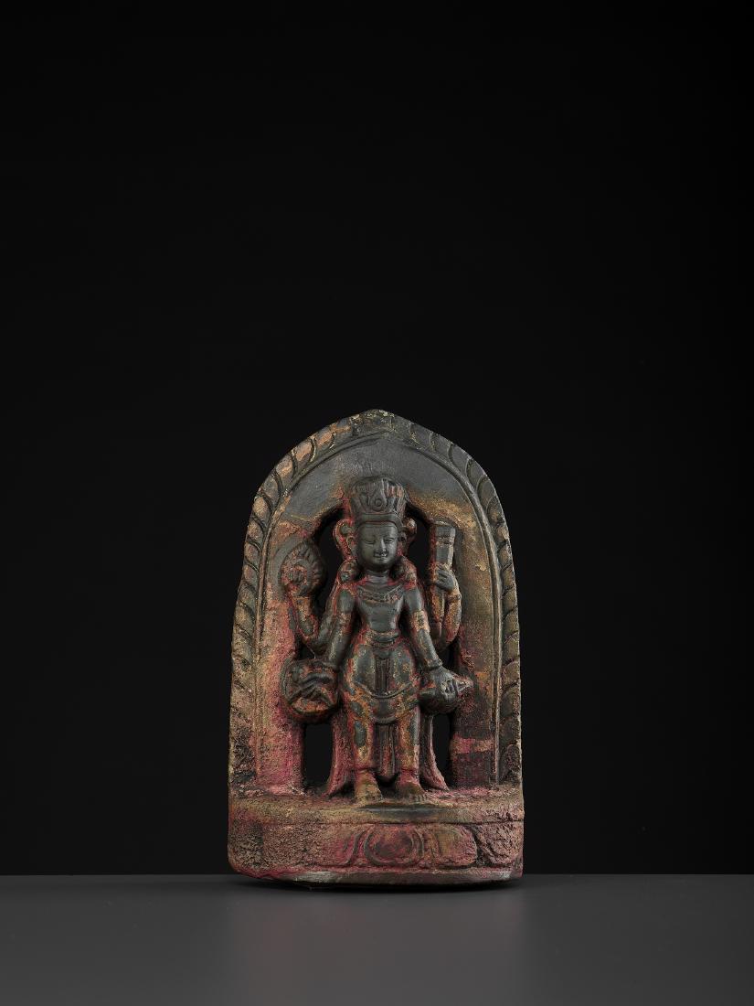 A NEPALESE STELE OF VISHNU, MALLA: A NEPALESE STELE OF VISHNU, MALLA 16th century. Newar, Kathmandu Valley, Malla period. Black fossiliferous limestone with remnants of old cold painting. Carved and incised in fine detail, the face wit