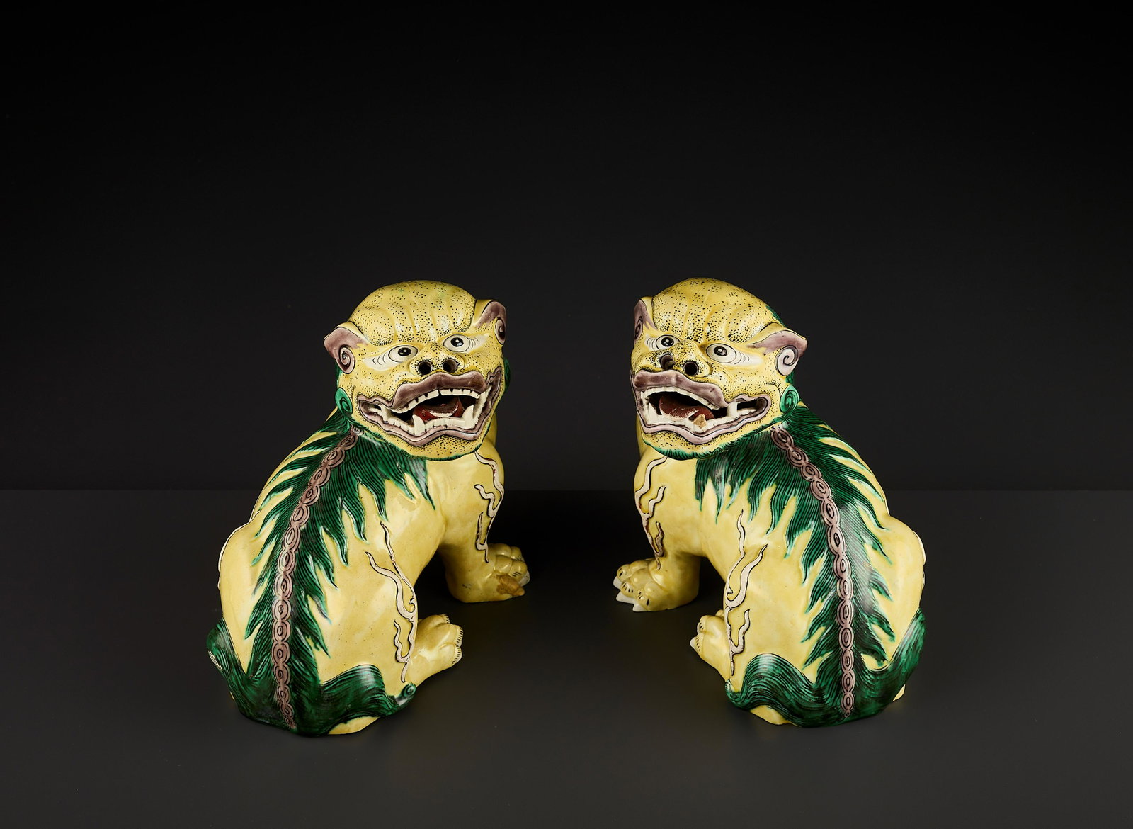 A RARE PAIR OF BUDDHIST LIONS, QING: A RARE PAIR OF BUDDHIST LIONS, QING China, 18th- 19th century. Heavily modeled to depict two fierce lions with open jaws, baring teeth, pierced nostrils, bulging eyes and protruding spine. Nicely glaz