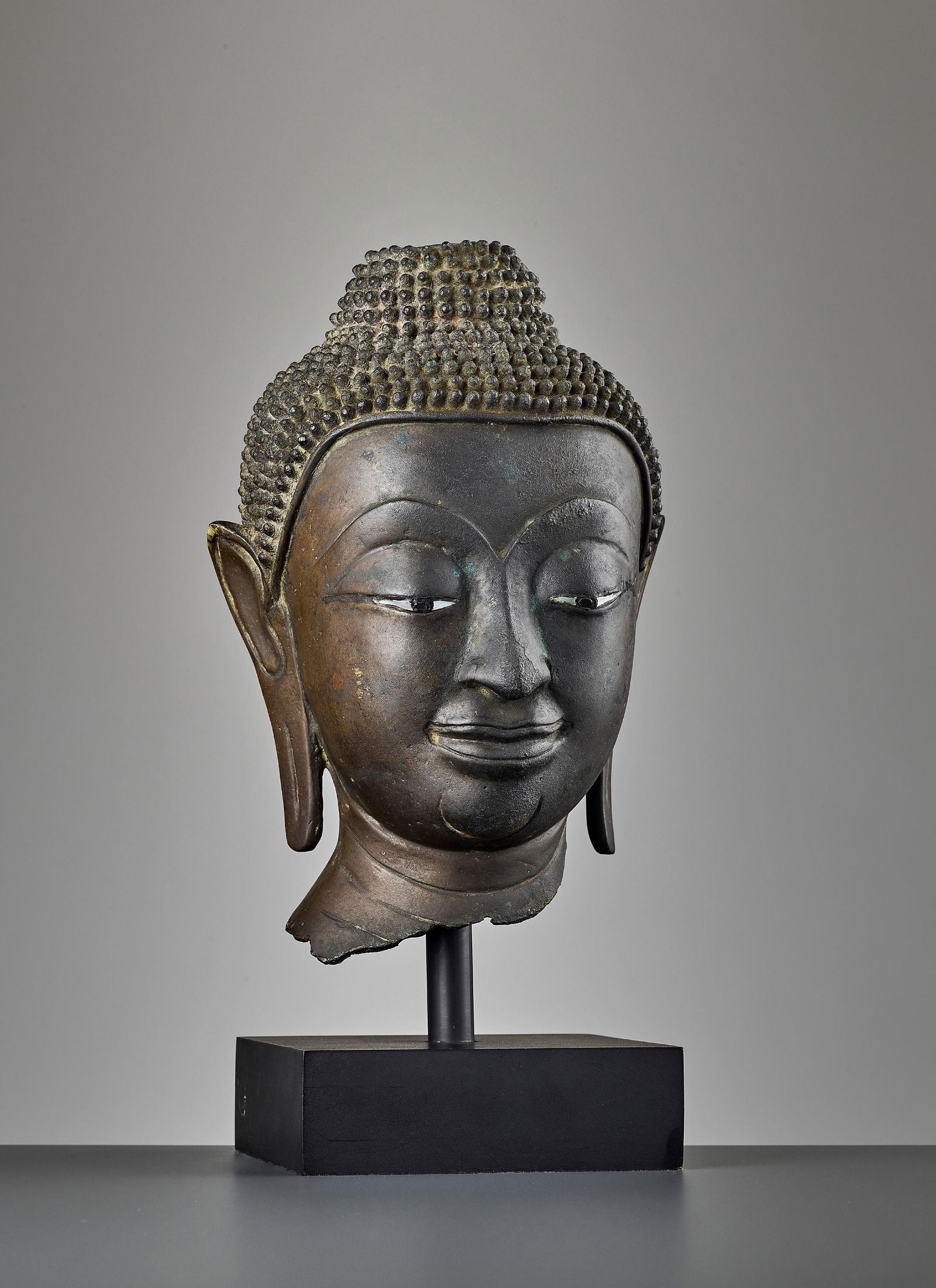 A SUKHOTHAI BRONZE HEAD OF BUDDHA, KAMPHAENG PHET: A SUKHOTHAI BRONZE HEAD OF BUDDHA, KAMPHAENG PHET Thailand, 15th century. Bronze with eyes inlaid in mother-of-pearl and black lacquer. The face bearing important Kamphaeng Phet style features such as