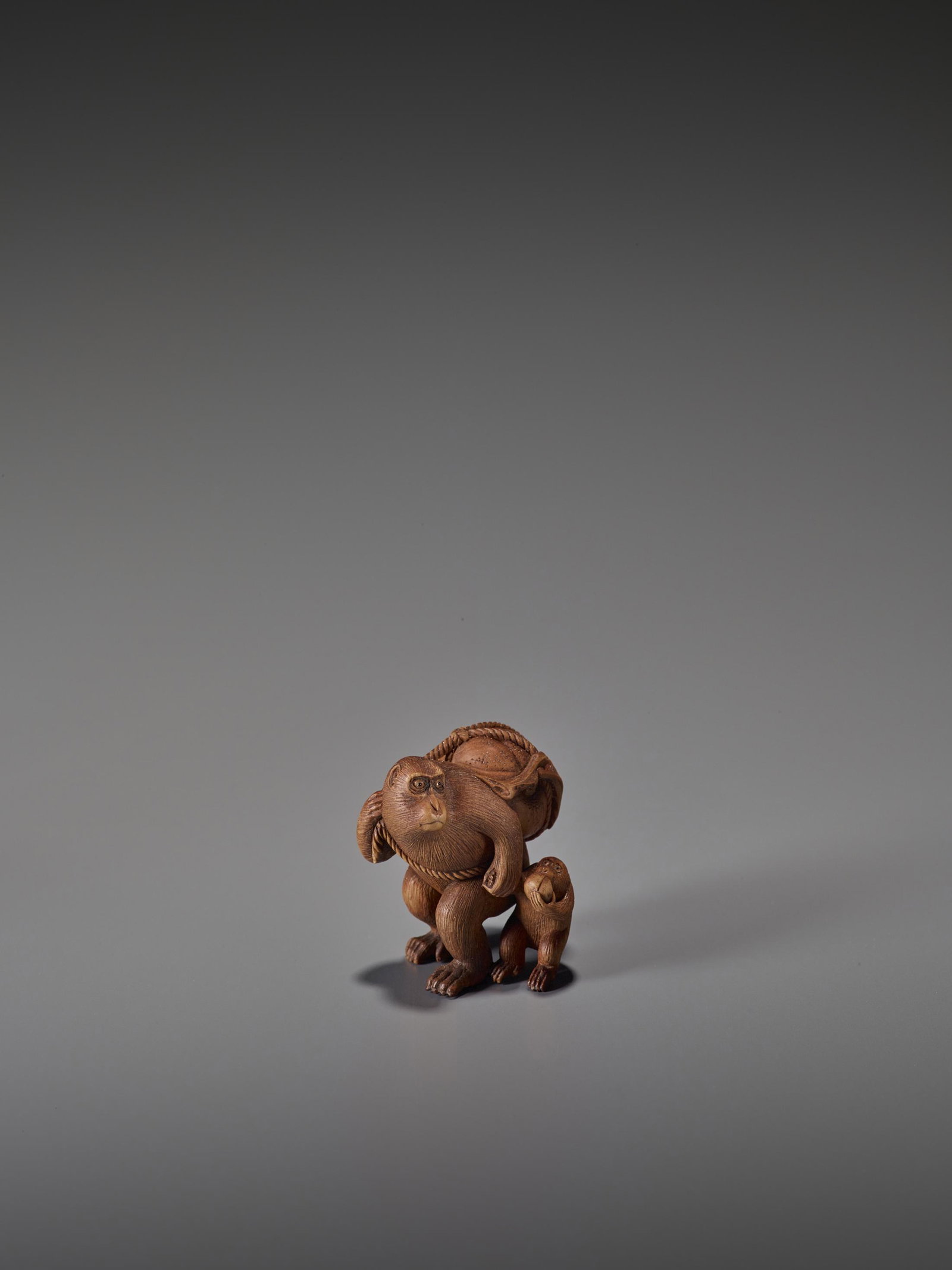 MASANOBU: WOOD NETSUKE OF TWO MONKEYS: MASANOBU: A CHARMING WOOD NETSUKE OF TWO MONKEYS WITH PEACHES By Masanobu, signed Masanobu Japan, Meiji period (1868-1912) Carved from a reddish wood and depicting an adult monkey holding its young by