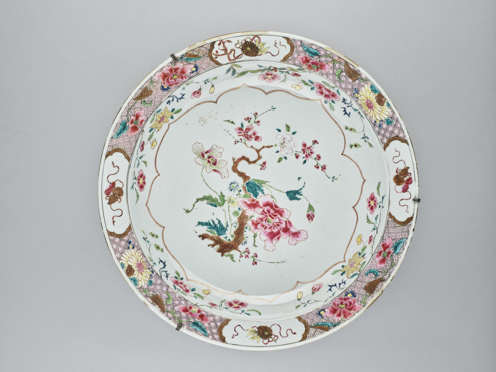 A GILT AND FAMILLE ROSE ENAMELED CHARGER, QING: A GILT AND FAMILLE ROSE ENAMELED CHARGER, QING China, 18th century. Painted with flowers in the well and Buddhist symbols along with further floral patterns on the lip, all with gilt highlights, and i