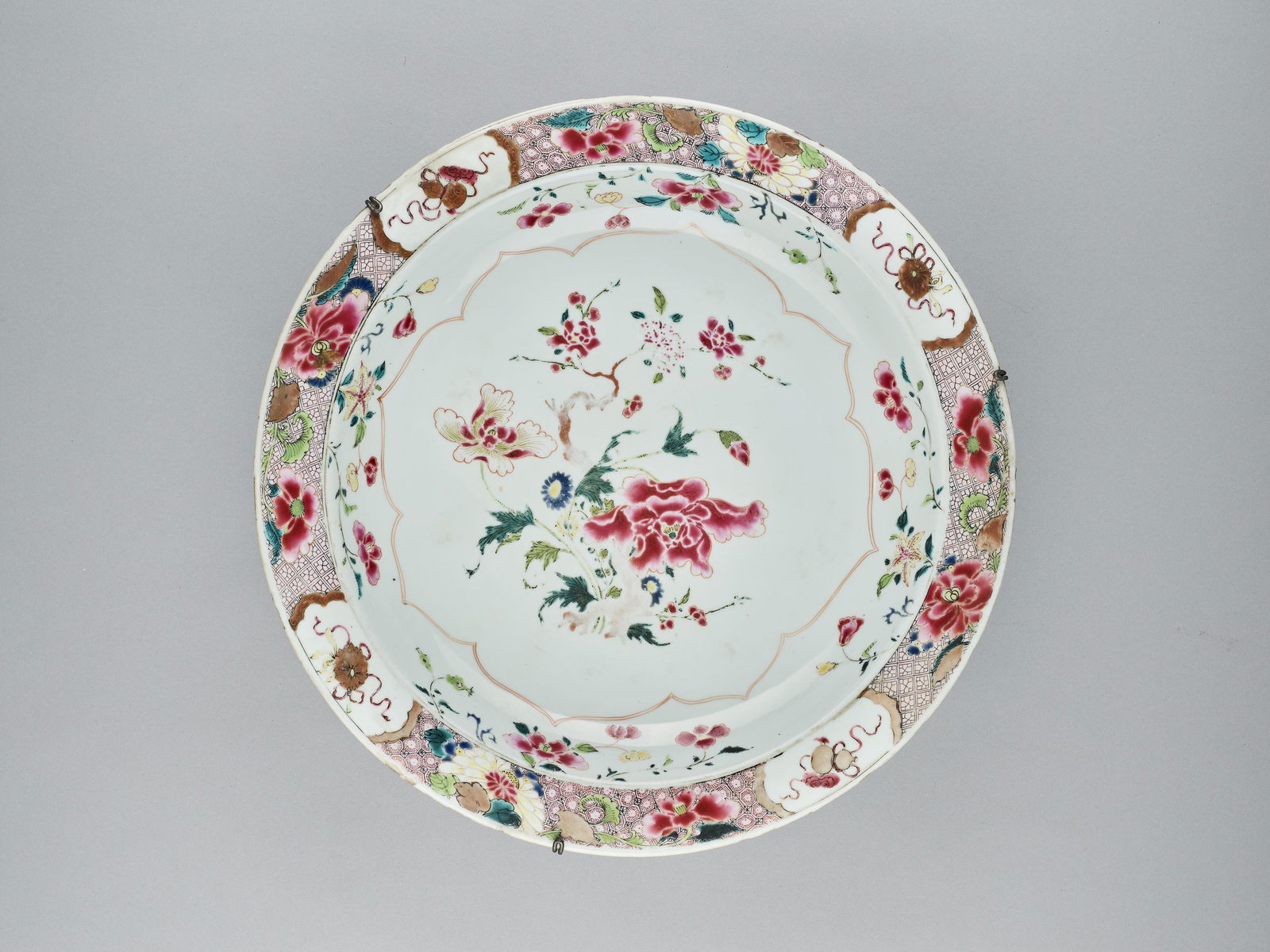 A FAMILLE ROSE CHARGER, QING: A FAMILLE ROSE CHARGER, QING China, 18th century. Painted with flowers in the well and Buddhist symbols with gilt highlights along with further floral patterns on the lip. Condition: Fritting and some