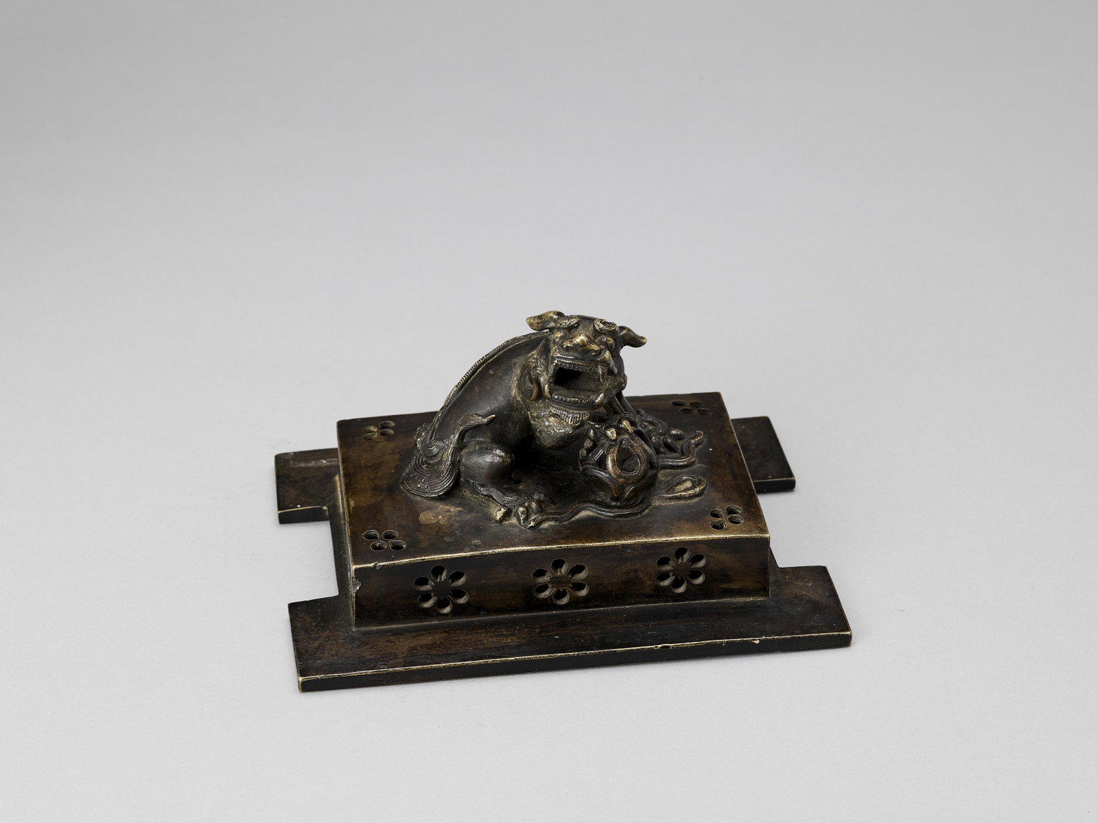 A MASSIVE CAST BRONZE LID FOR A CENSER, MING: A MASSIVE CAST BRONZE LID FOR A CENSER WITH A BUDDHIST LION, MING China, 1368-1644. The pierced cast bronze censer lid is topped by a large and fierce Buddhist lion with a brocade ball. Old collector'