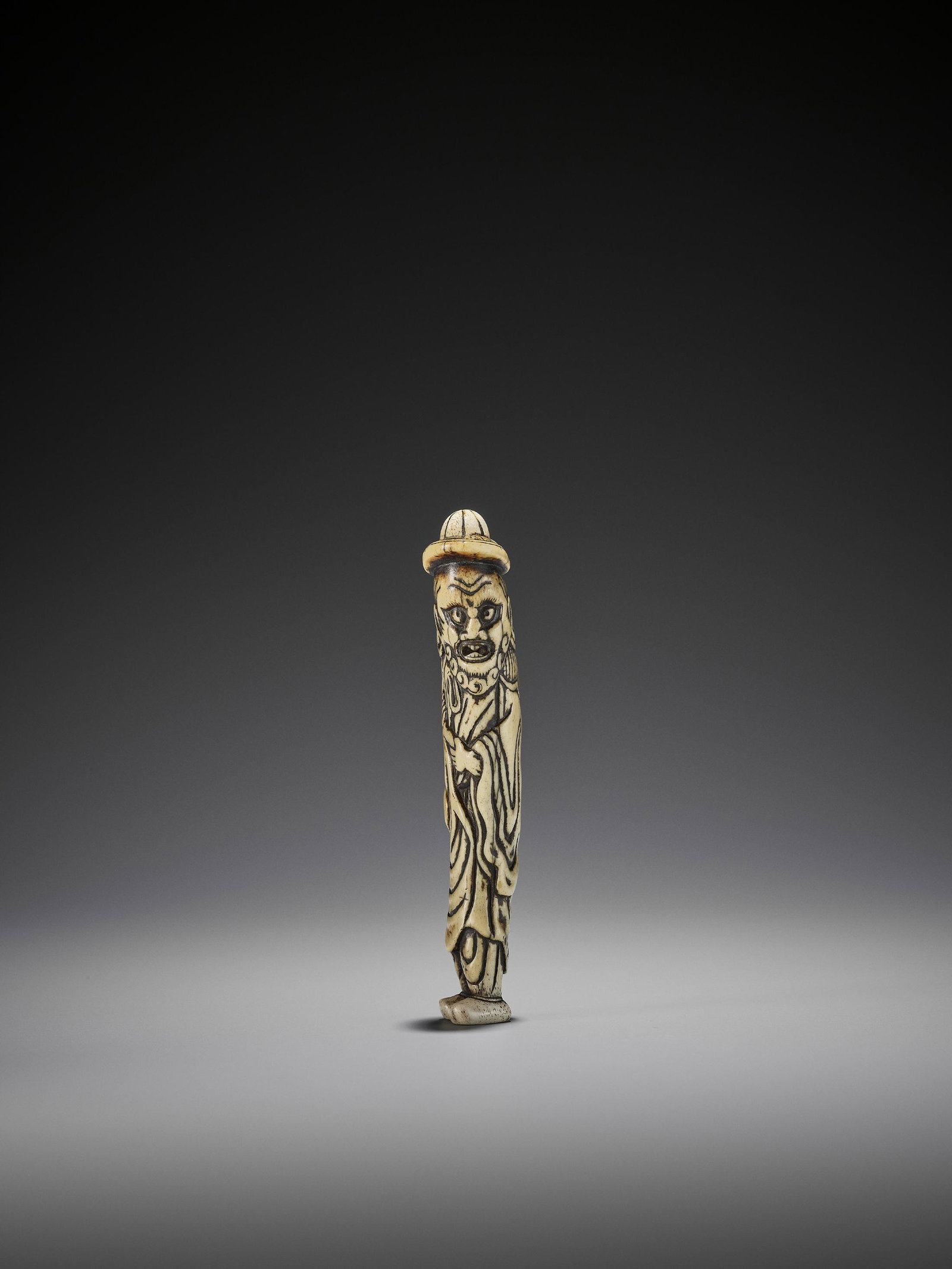 EARLY AND TALL STAG ANTLER NETSUKE OF A DUTCHMAN: AN EARLY AND TALL STAG ANTLER NETSUKE OF A DUTCHMAN Unsigned Japan, 18th century, Edo period (1615-1868) An early netsuke carved from stag antler which has developed a very appealing patina. The Dutch