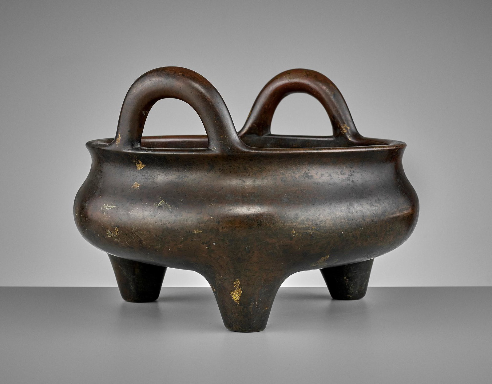 A LARGE BRONZE TRIPOD CENSER, 17TH CENTURY: A LARGE AND HEAVILY CAST BRONZE TRIPOD CENSER, 17TH CENTURY China, late Ming to early Qing dynasty. The compressed globular body raised on three short conical feet, the slightly everted rim set with t