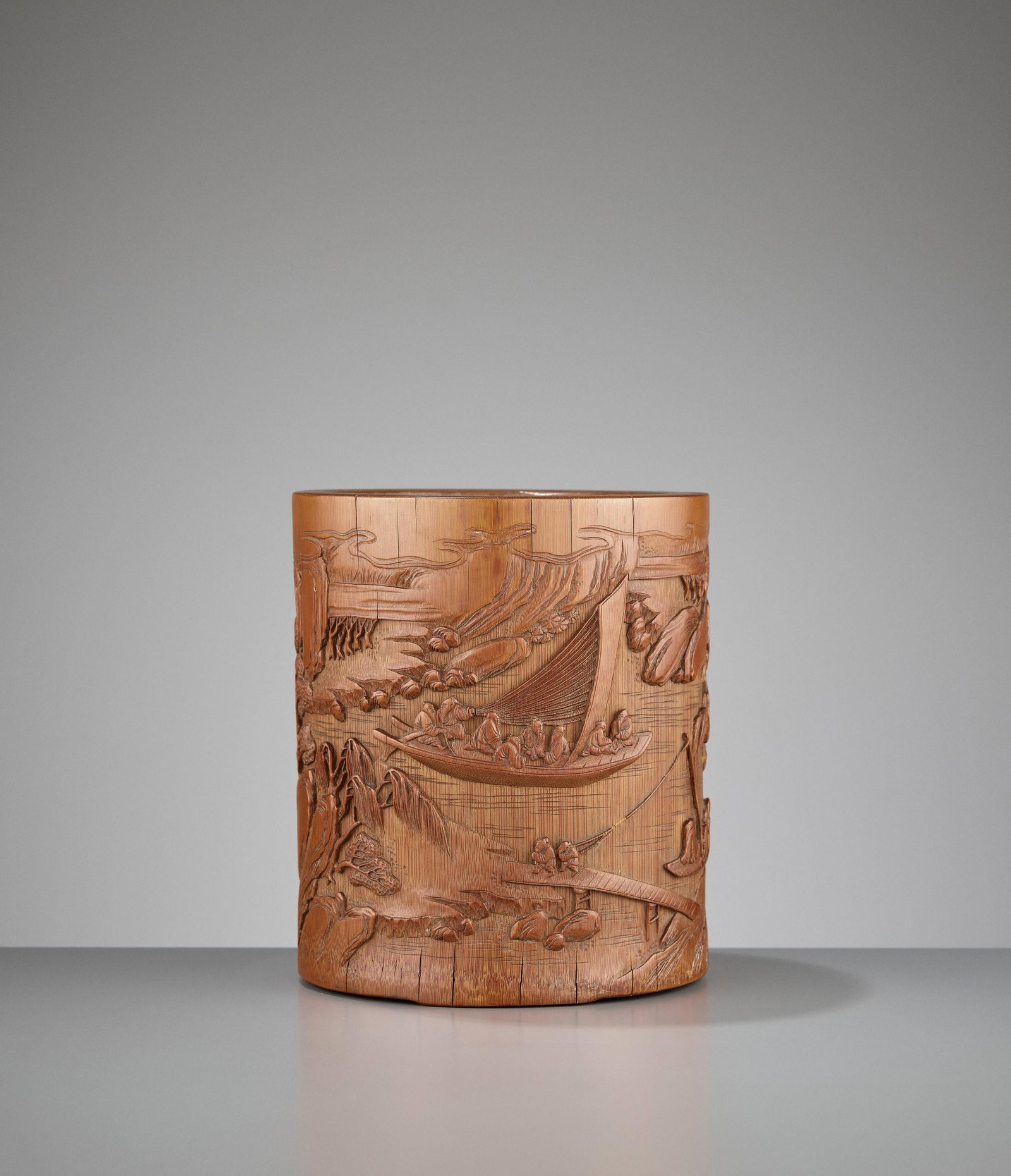 A BAMBOO BRUSH POT BY WANG JICHANG, QIANLONG: A BAMBOO 'BOATING' BRUSH POT BY WANG JICHANG, QIANLONG PERIOD China, 1735-1796. Intricately carved with a majestic lakeshore landscape, depicted with an elderly man looking out from a small open pavil