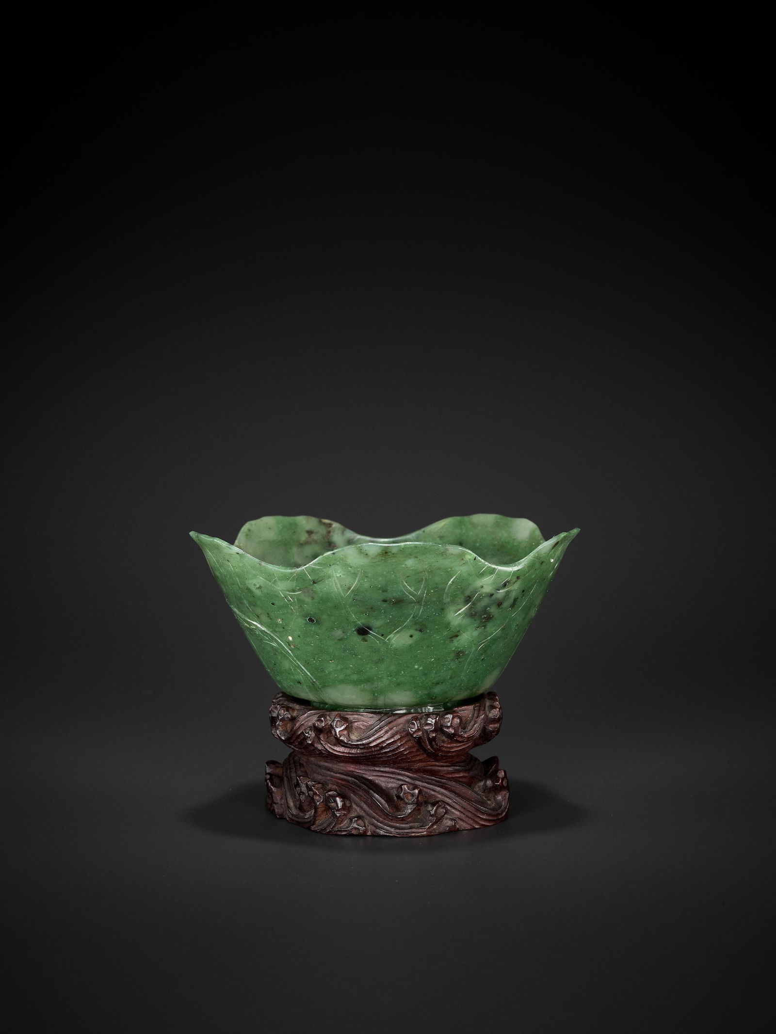 A SPINACH GREEN JADE BRUSH WASHER, QING DYNASTY: A SPINACH GREEN JADE BRUSH WASHER, XI, QING DYNASTY China, late 18th-19th century. The thinly lobed lip enables simultaneous use as a washer and a brush rest. The translucent stone is thinly carved as