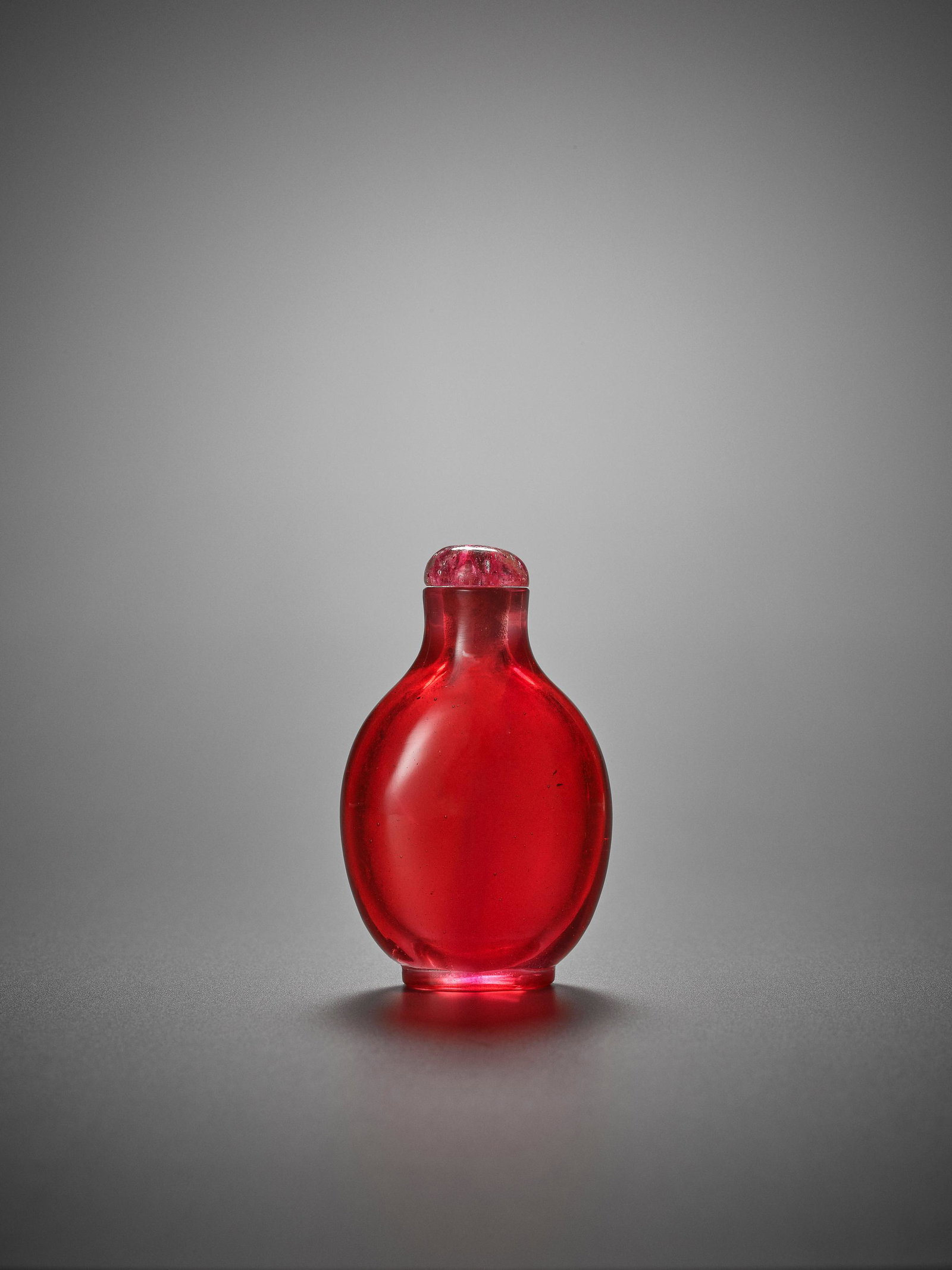 AN IMPERIAL RUBY-PINK GLASS SNUFF BOTTLE: AN IMPERIAL RUBY-PINK GLASS SNUFF BOTTLE China, 1740-1800. The translucent pink glass around the foot gradually fading into a transparent, bubble-suffused body, smooth surface polish. Large mouth and 