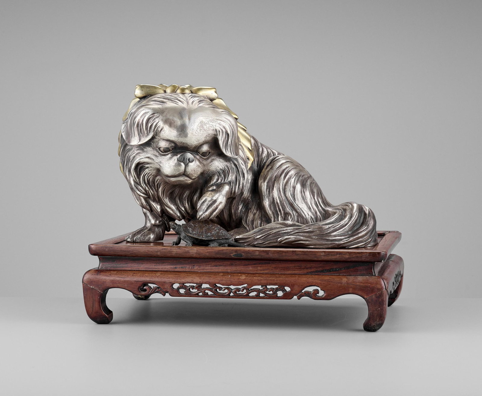 MARUKI: A LARGE SILVERED OKIMONO OF A CHIN DOG: MARUKI COMPANY: AN EXCEPTIONAL AND LARGE PARCEL-GILT AND SILVERED OKIMONO OF A CHIN DOG By the Maruki Company, signed Maruki shachu seisaku Japan, Meiji period (1868-1912) Naturalistically modeled sea