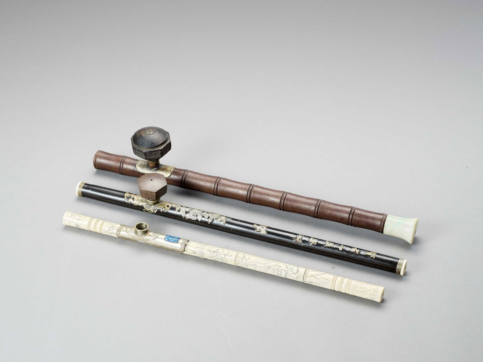 THREE OPIUM PIPES, LATE QING TO REPUBLIC: THREE OPIUM PIPES, LATE QING TO REPUBLIC China, late Qing dynasty (1644-1912) to Republic period (1912-1949). One carved from bamboo with a metal bowl and a jadeite mouthpiece. Another lacquered in bl