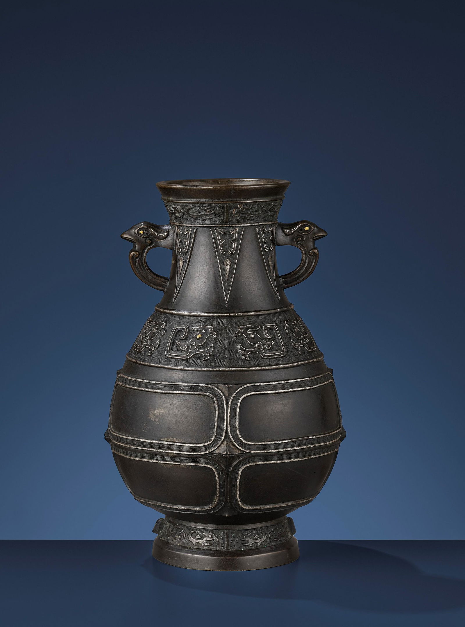 A PARCEL-GILT SILVER-INLAID 'CARDINAL POINTS' HU, MING: A PARCEL-GILT AND SILVER-INLAID 'CARDINAL POINTS' VASE, HU, MING DYNASTY China, 1368-1644. The pear-shaped bronze body is divided into four equal sections, indicating the four cardinal points, all dis