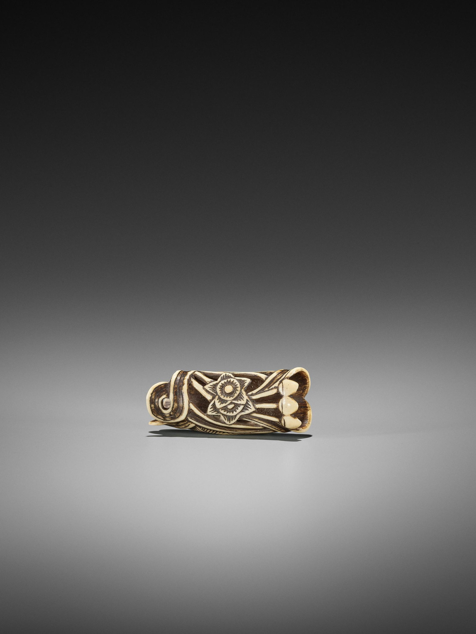 A STAG ANTLER NETSUKE DEPICTING ACORNS: A STAG ANTLER NETSUKE DEPICTING ACORNS Japan, 18th century, Edo period (1615-1868) Carved in openwork from a hollow branch of stag antler and depicting a bundle of acorns. One pierced himotoshi and on