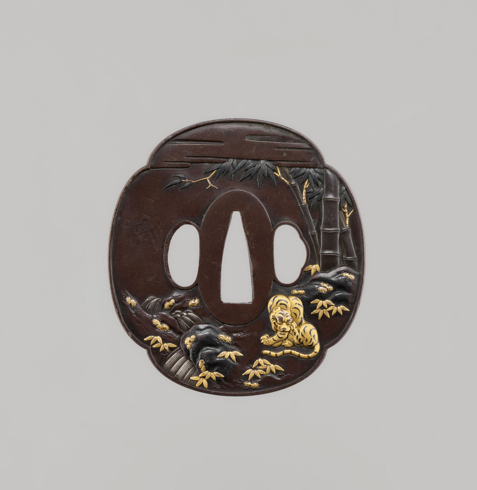 A SHIBUICHI TSUBA WITH TIGER, BAMBOO, & WATERFALL: A GOTO SCHOOL SHIBUICHI TSUBA WITH TIGER, BAMBOO, AND WATERFALL Japan, 19th century, Edo period (1615-1868) The shibuichi tsuba of mokkogata shape, very finely worked in high relief with silver highli