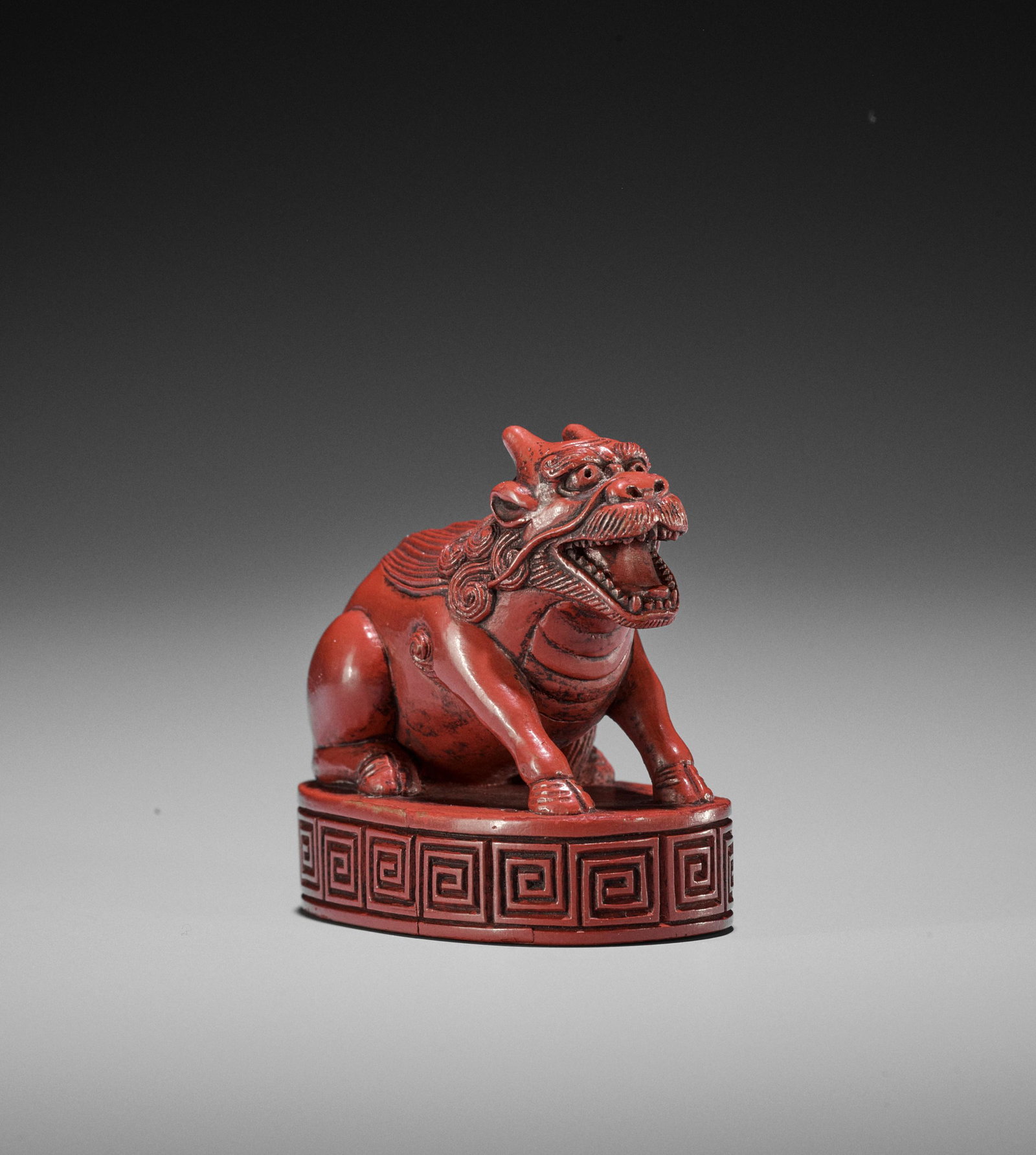 A TSUISHU LACQUER INGYO (SEAL) NETSUKE OF A KIRIN: A TSUISHU LACQUER INGYO (SEAL) NETSUKE OF A KIRIN Japan, 19th century, Edo period (1615-1868) The seal of oval form with an incised key-fret pattern to the sides, surmounted by a two-horned kirin seat