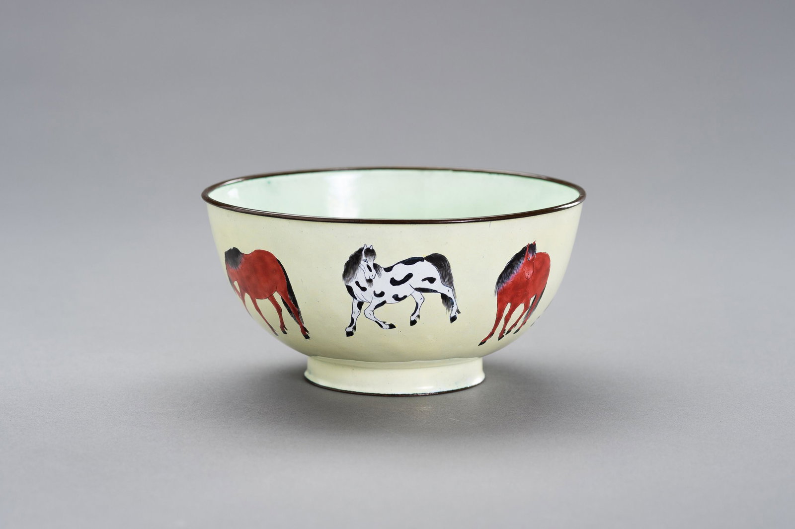AN ENAMEL ON COPPER `WANG MU' BOWL: AN ENAMEL ON COPPER `WANG MU' BOWL China, Republic period (1912-1949). The deep sided bowl rising from a ring foot. Finely enameled on a pale yellow ground with seven of the eight horses of King Mu. T