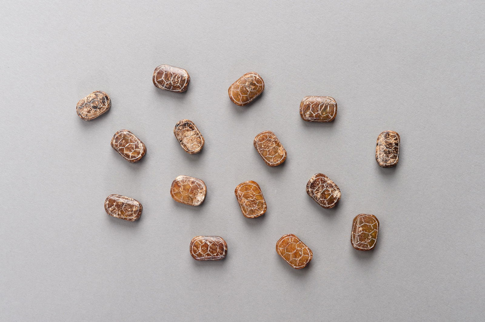 A LOT OF FIFTEEN NEPHRITE 'TORTOISE' BEADS: A LOT OF FIFTEEN NEPHRITE 'TORTOISE' BEADS China, Ming Dynasty (1368-1644). Fifteen beads, almost identical in size beads, hand carved in the shape of empty tortoise shells from opaque nephrite of gre