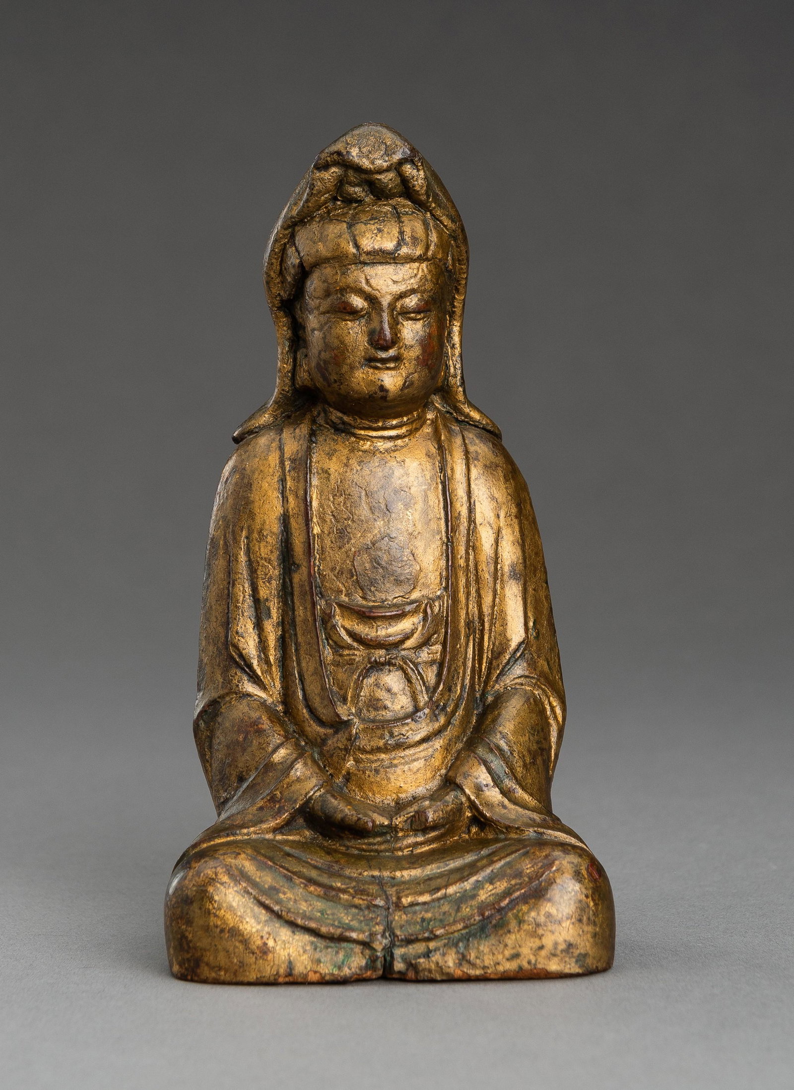 A GOLD LACQUERED WOOD FIGURE OF GUANYIN, 19th CENTURY: A GOLD LACQUERED WOOD FIGURE OF GUANYIN, 19th CENTURY China, Qing Dynasty (1644-1912). Seated in dhyanasana with hands lowered in dhyana mudra, the face with a serene expression and downcast eyes, the