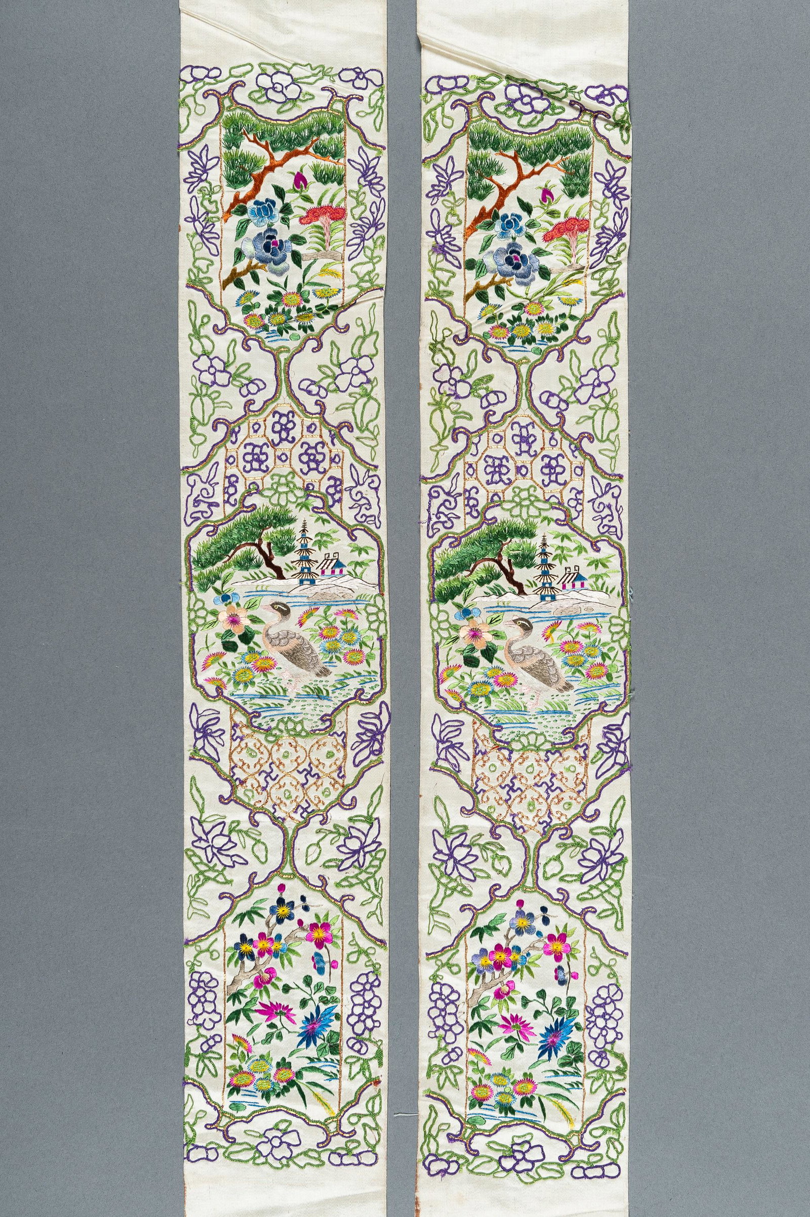 A PAIR OF FLORAL SILK SLEEVE BANDS, QING: A PAIR OF FLORAL SILK SLEEVE BANDS, QING China, Qing Dynasty (1644-1912). Finely embroidered in Beijing knot and Satin stitch with gold threads, depicting reserves enclosing ducks, pagodas, trees, and