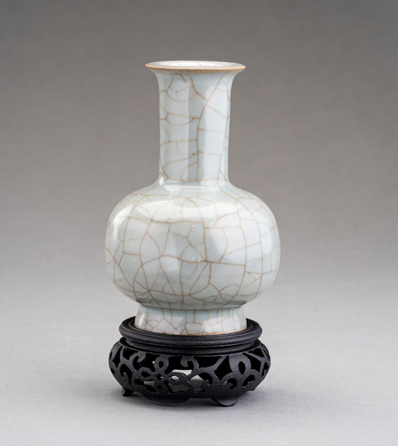 A GUAN-STYLE CELADON GLAZED PORCELAIN BOTTLE VASE, QING DYNASTY: A GUAN-STYLE CELADON GLAZED PORCELAIN BOTTLE VASE, QING DYNASTY China, late Qing Dynasty (1644-1912), 19th century. The bulbous body rising from a splayed foot to an elongated neck with flared rim, co