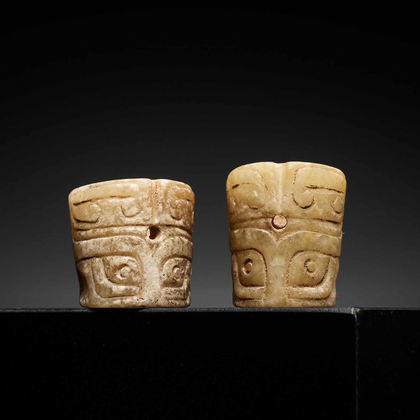 TWO YELLOW JADE 'TAOTIE' BEADS, SHANG TO WESTERN ZHOU DYNASTY: TWO YELLOW JADE 'TAOTIE' BEADS, SHANG TO WESTERN ZHOU DYNASTY China, c. 1600-771 BC. Each of slightly tapering form, thickly walled with a central channel drilled from both sides, the exterior carved 