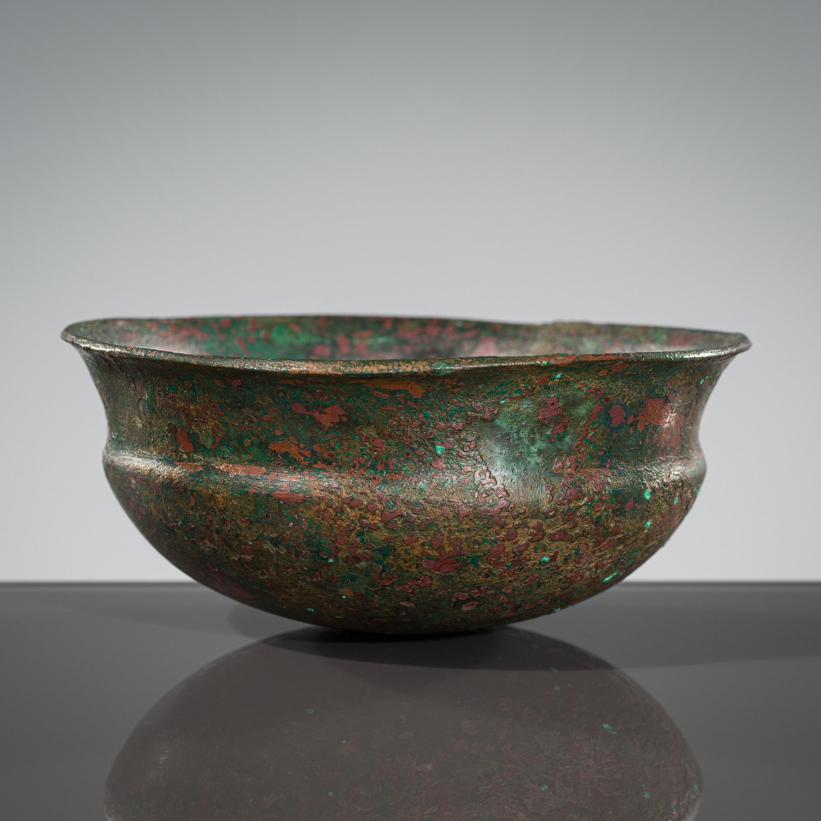 A BRONZE BOWL, XI, HAN DYNASTY: A BRONZE BOWL, XI, HAN DYNASTY China, 202 BC to 220 AD. Boldly cast with a circular base with a subtle shoulder surmounted by an everted rim. The simplistic vessel is covered in a rich, naturally grow