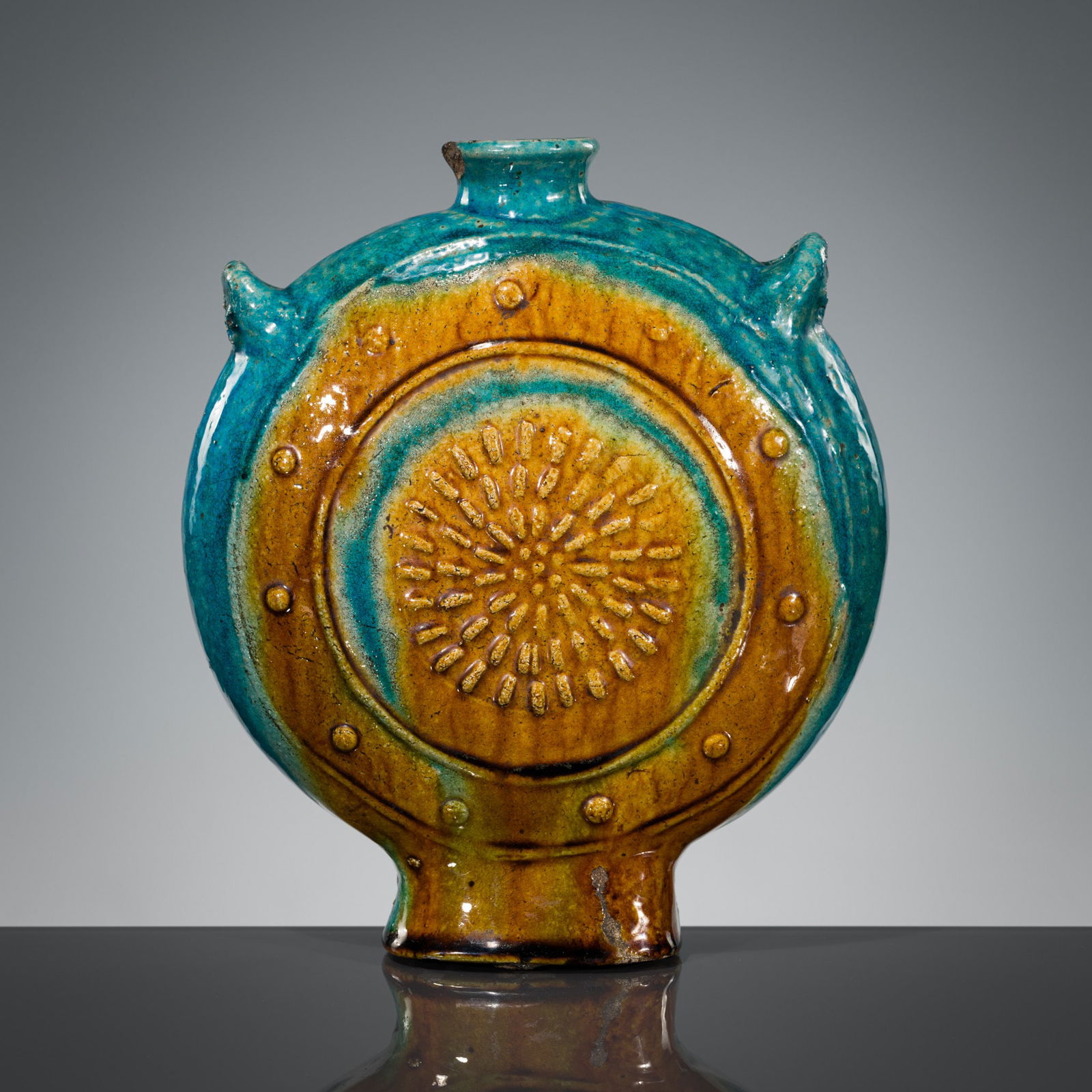 A TURQUOISE AND AMBER GLAZE 'LOTUS AND CHRYSANTHEMUM' MOON FLASK, BIANFU, LATE MING DYNASTY: A TURQUOISE AND AMBER GLAZE 'LOTUS AND CHRYSANTHEMUM' MOON FLASK, BIANFU, LATE MING DYNASTY China, 17th century. The flattened oval body raised on a spreading foot and rising to a waisted neck surmoun
