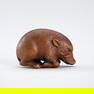 A WOOD NETSUKE OF A RECUMBENT BOAR
