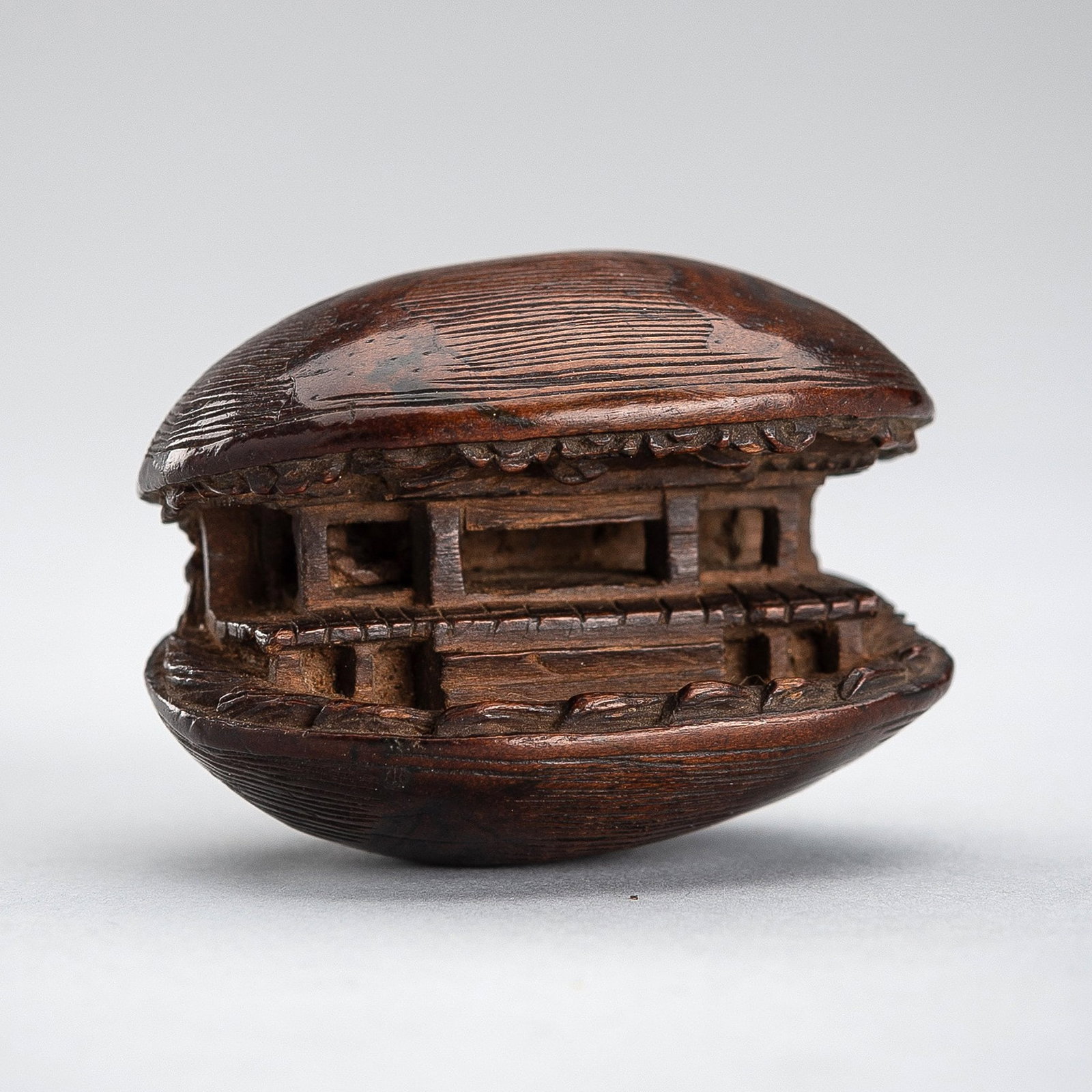 A WOOD NETSUKE OF THE CLAM'S DREAM: A WOOD NETSUKE OF THE CLAM'S DREAM Unsigned Japan, 19th century, Edo period (1615-1868) Finely modeled as a clam revealing from within its depths the insides of a pavilion rendere