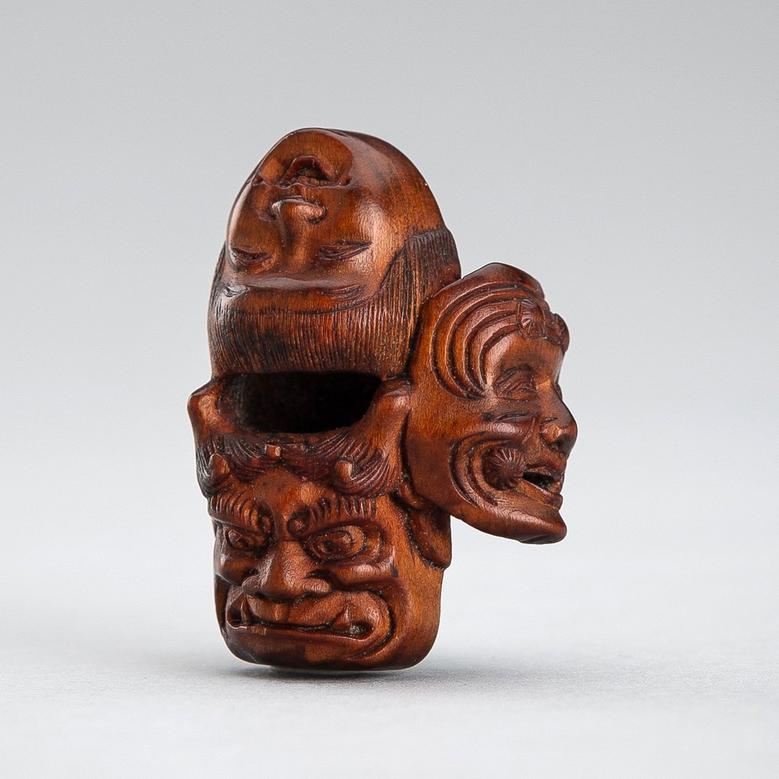 GYOKUZAN: A WOOD NETSUKE OF A CLUSTER OF FOUR MASKS (1 of 11)