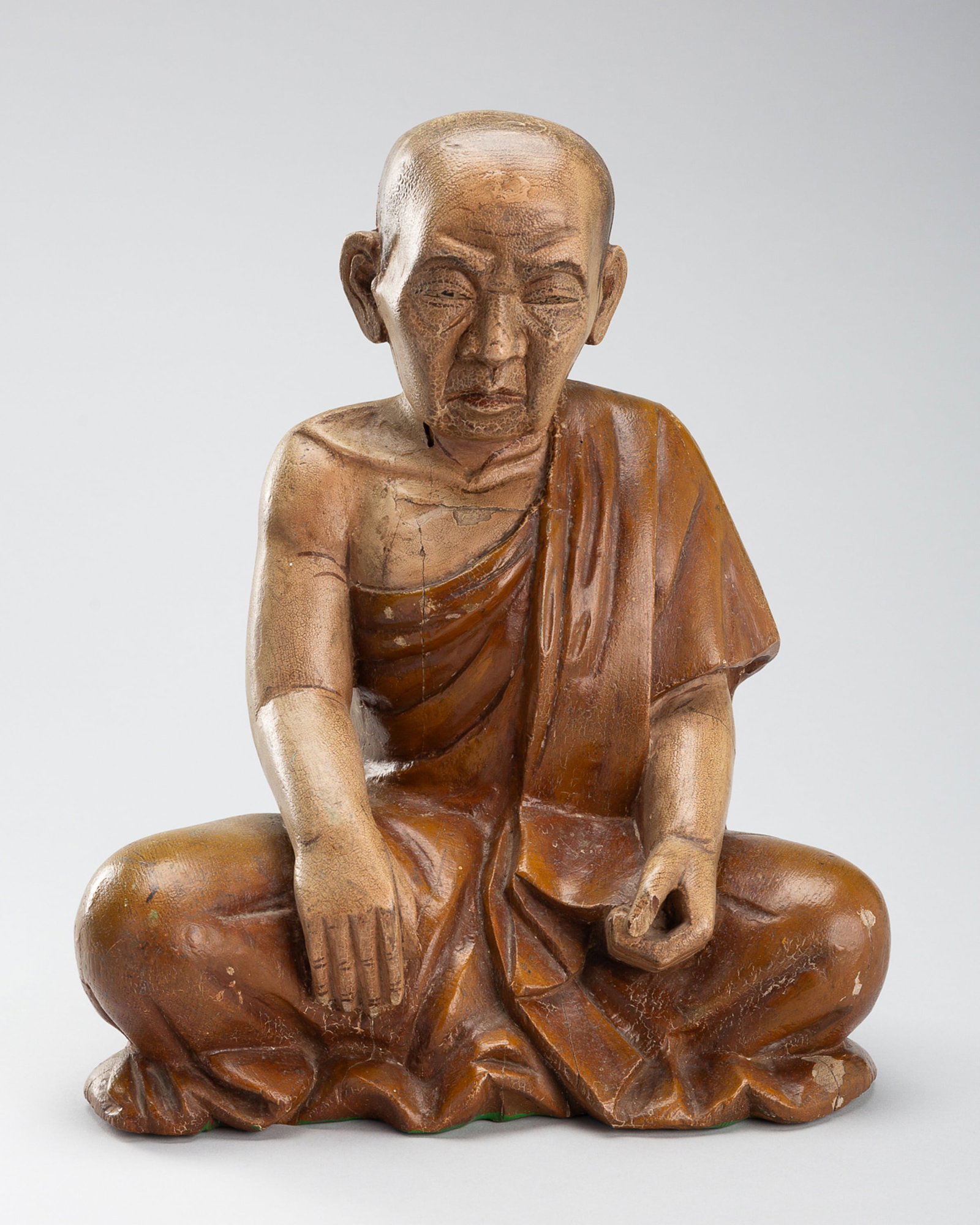 A LACQUERED WOOD FIGURE OF AN ELDERLY MONK: A LACQUERED WOOD FIGURE OF AN ELDERLY MONK Southeast Asia, 19th century. Seated in dhyanasana, with his right hand lowered in bhumisparsha mudra, his left hand cupped in his lap. His aged face finely 