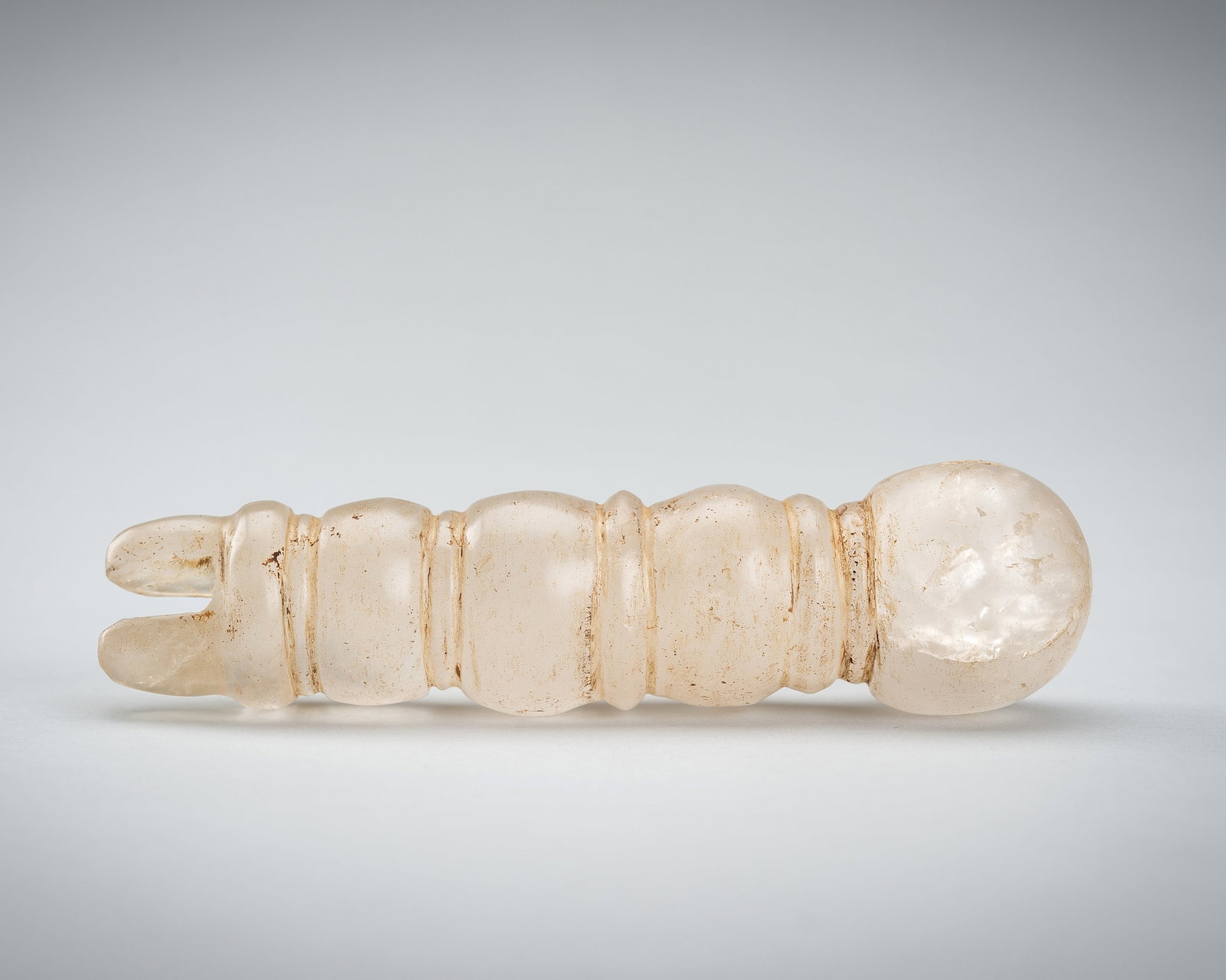 A ROCK CRYSTAL FRAGMENT, 1ST - 4TH CENTURY: A ROCK CRYSTAL FRAGMENT, 1ST - 4TH CENTURY Southeast Asia, 1st-4th century or earlier. The tapering body carved with ribs, topped by a globular knob and flanges to the bottom. The translucent stone wi