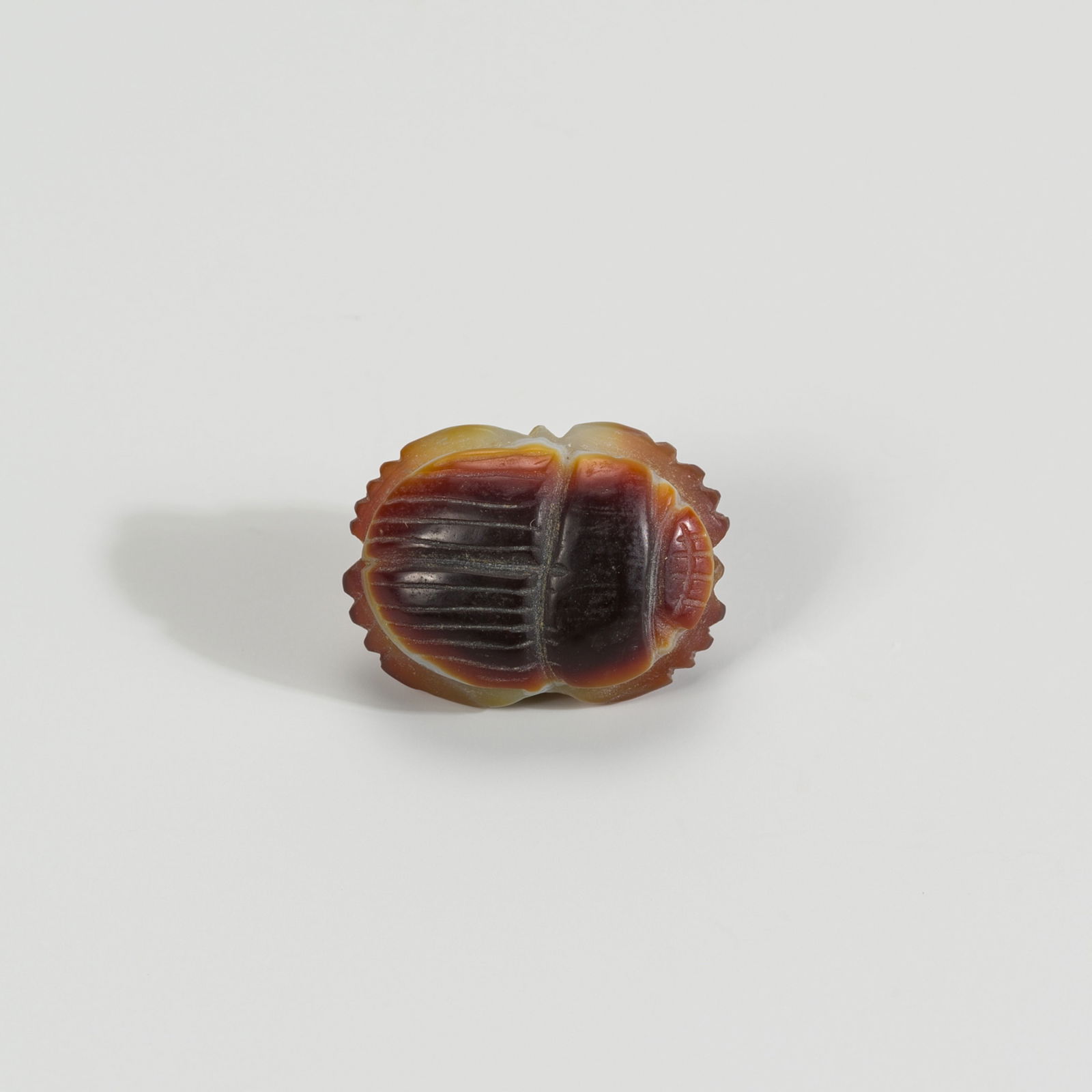 A SMALL AGATE 'SCARAB' TALISMAN, 10TH-12TH CENTURY AD OR LATER: A SMALL AGATE 'SCARAB' TALISMAN, 10TH-12TH CENTURY AD OR LATER Middle East, 10th-12th century AD or later. Carved in the form of a scarab beetle, drilled through the center for suspension as a pendant