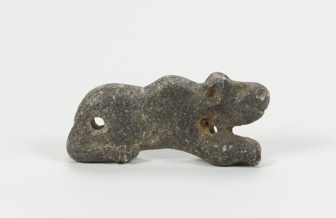 A NEAR EAST GRAY STONE 'TIGER' AMULET: A NEAR EAST GRAY STONE 'TIGER' AMULET Near East, late 2nd – 1st Millennium BC. Carved in the form of a crouching tiger, the feet tucked under the body, the face with pricked ears and circular ey