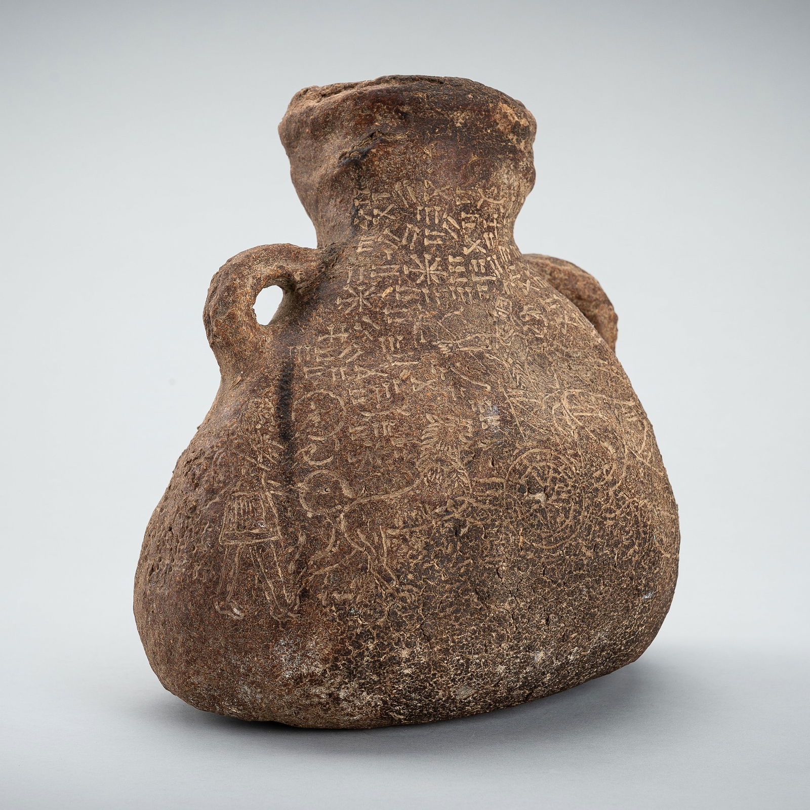 A LEATHER VESSEL INCISED WITH CUNEIFORM SCRIPT AND FIGURES (1 of 12)