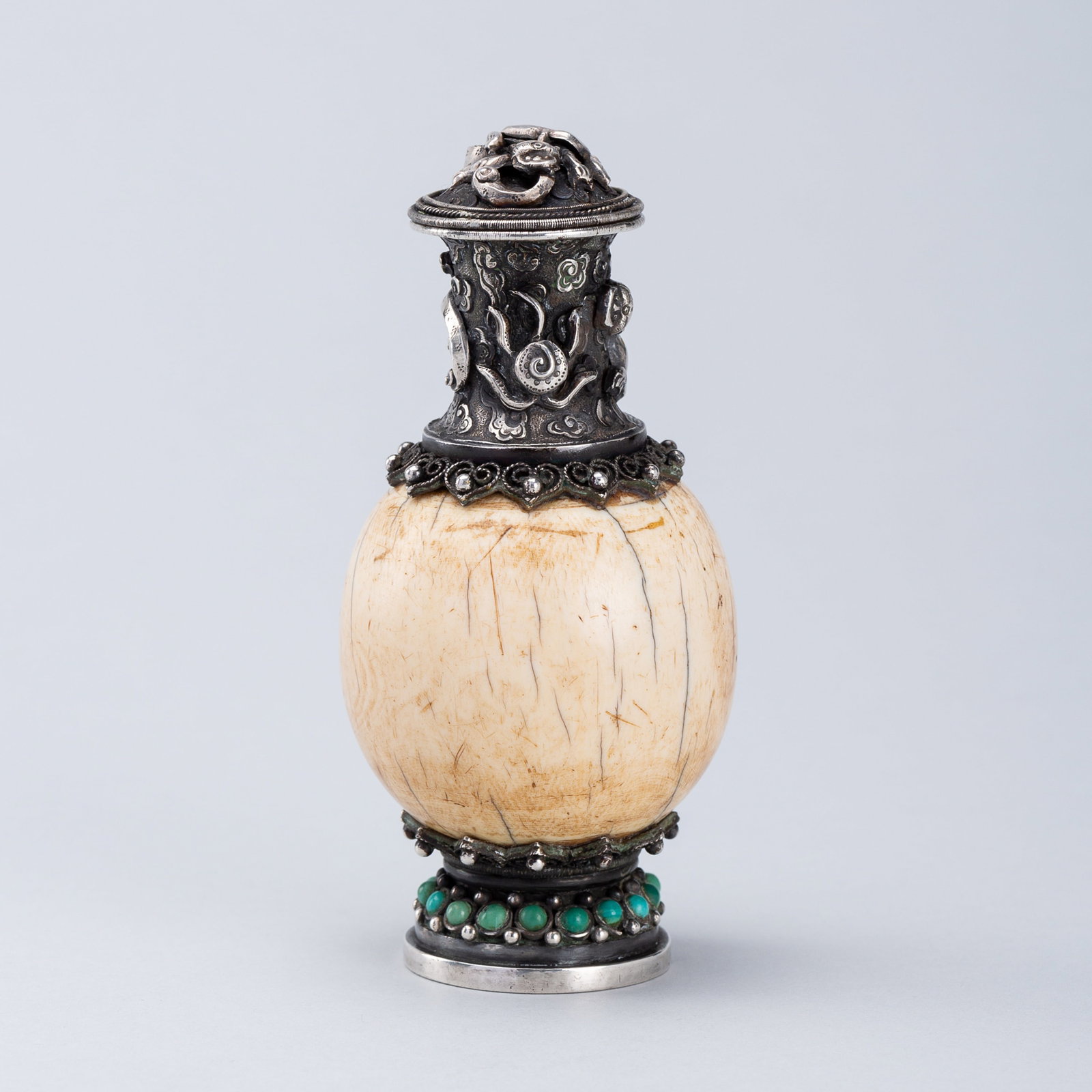 A SILVER-PLATED BONE SNUFF BOTTLE, 19TH CENTURY: A SILVER-PLATED BONE SNUFF BOTTLE, 19TH CENTURY Mongolia. The round bone body fitted with silver plated mountings to the foot and neck, and embellished with filigree work and turquoise insets, the nec