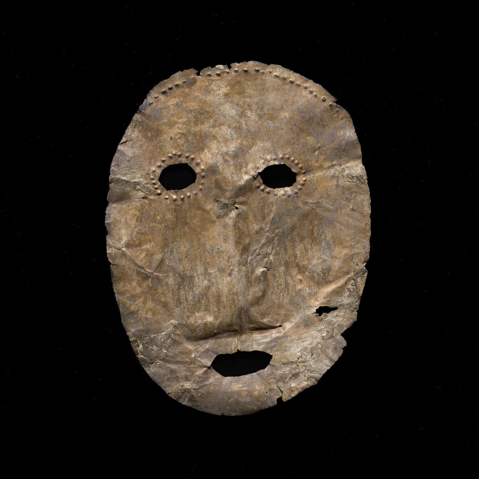 A SIBERIAN YAKUT GUARDIAN SPIRIT REPOUSSE MASK, 19TH CENTURY OR EARLIER: A SIBERIAN YAKUT GUARDIAN SPIRIT REPOUSSE MASK, 19TH CENTURY OR EARLIER North-Eastern Russia. The metal is thinly hammered, the oval mask pierced with two round eyes encircled by embossed nodes, a sma