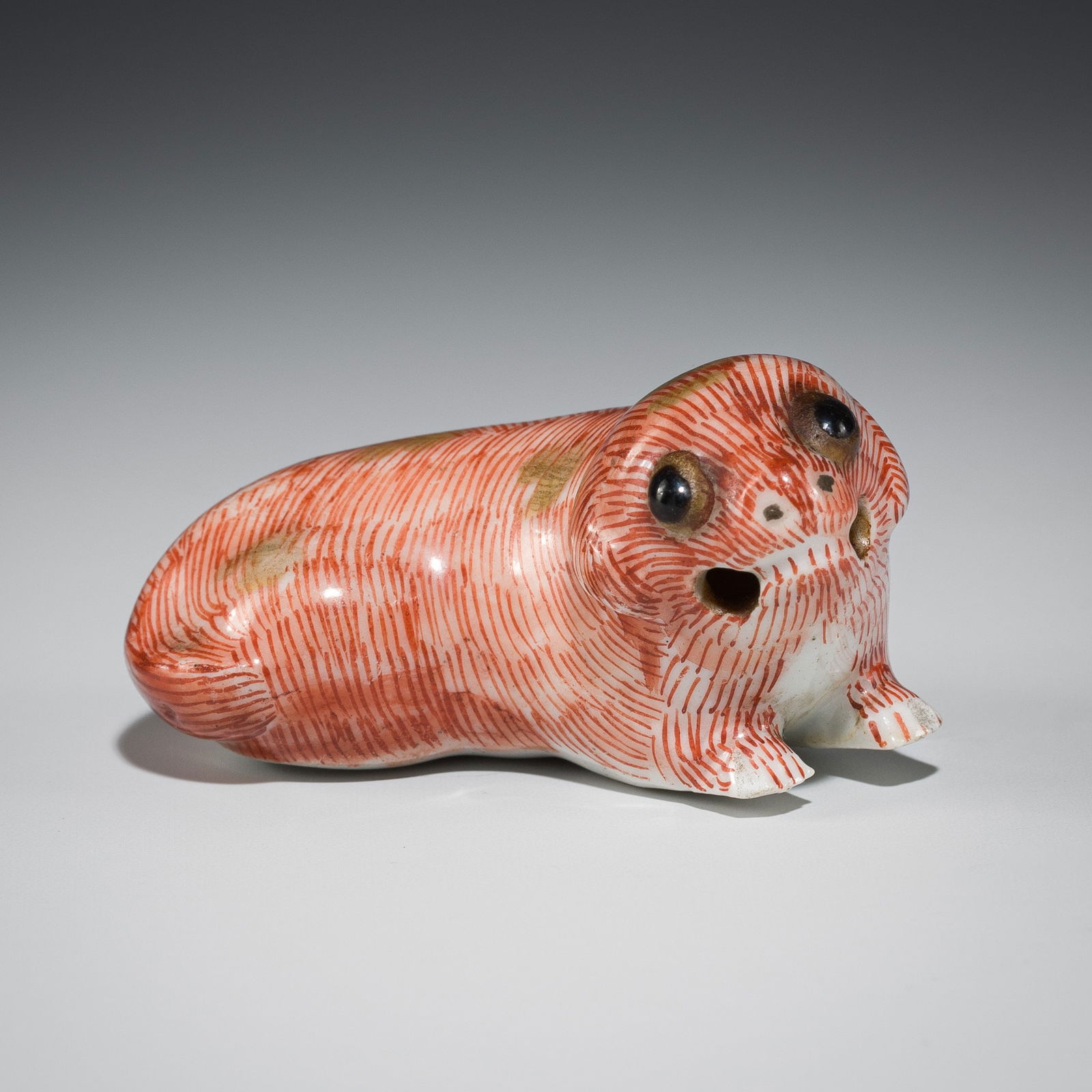 A PORCELAIN NETSUKE OF A RECUMBENT DOG (1 of 9)