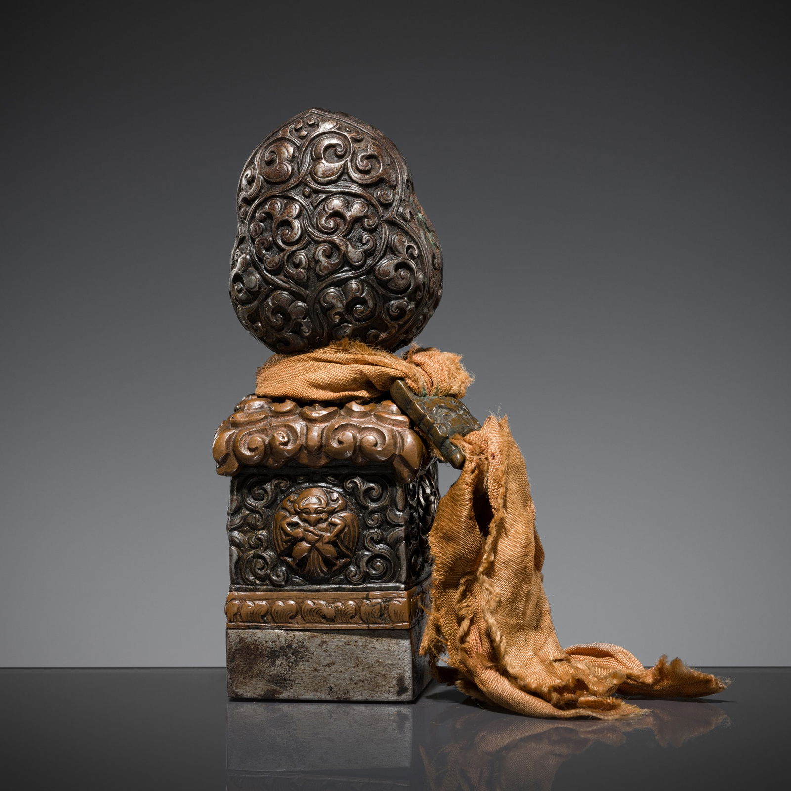 AN IRON AND COPPER ALLOY SEAL, TIBET, 18TH-19TH CENTURY: AN IRON AND COPPER ALLOY SEAL, TIBET, 18TH-19TH CENTURY This lot is a museum deaccession and is therefore offered without reserve Of square form, finely worked to the body with four domed roundels dep