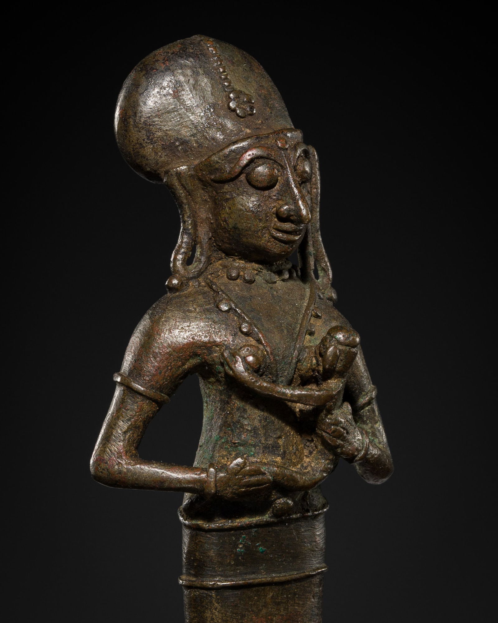 A BRONZE FIGURE OF YASHODA WITH THE INFANT KRISHNA, SOUTH INDIA, 15TH-17TH CENTURY: A BRONZE FIGURE OF YASHODA WITH THE INFANT KRISHNA, SOUTH INDIA, 15TH-17TH CENTURY Well cast standing atop a circular base, wearing a long dhoti and adorned with plain beaded jewelry, holding an infan