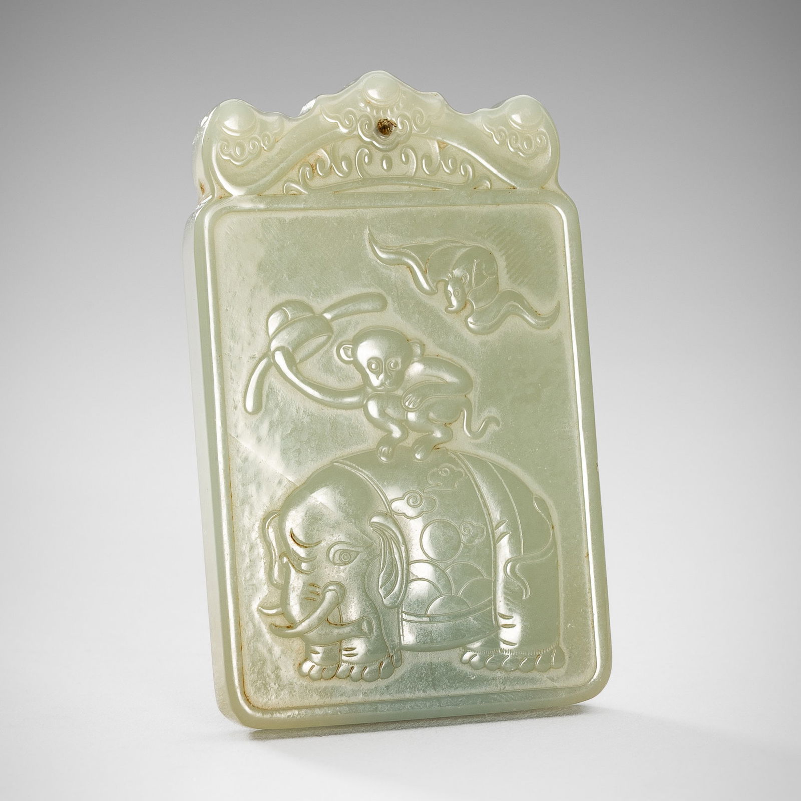 A PALE CELADON JADE 'MONKEY AND ELEPHANT' PLAQUE, LATE QING DYNASTY TO REPUBLIC PERIOD: A PALE CELADON JADE 'MONKEY AND ELEPHANT' PLAQUE, LATE QING DYNASTY TO REPUBLIC PERIOD China, c. 1900s. The rectangular plaque carved to one side with a monkey riding an elephant and a bat flying abov
