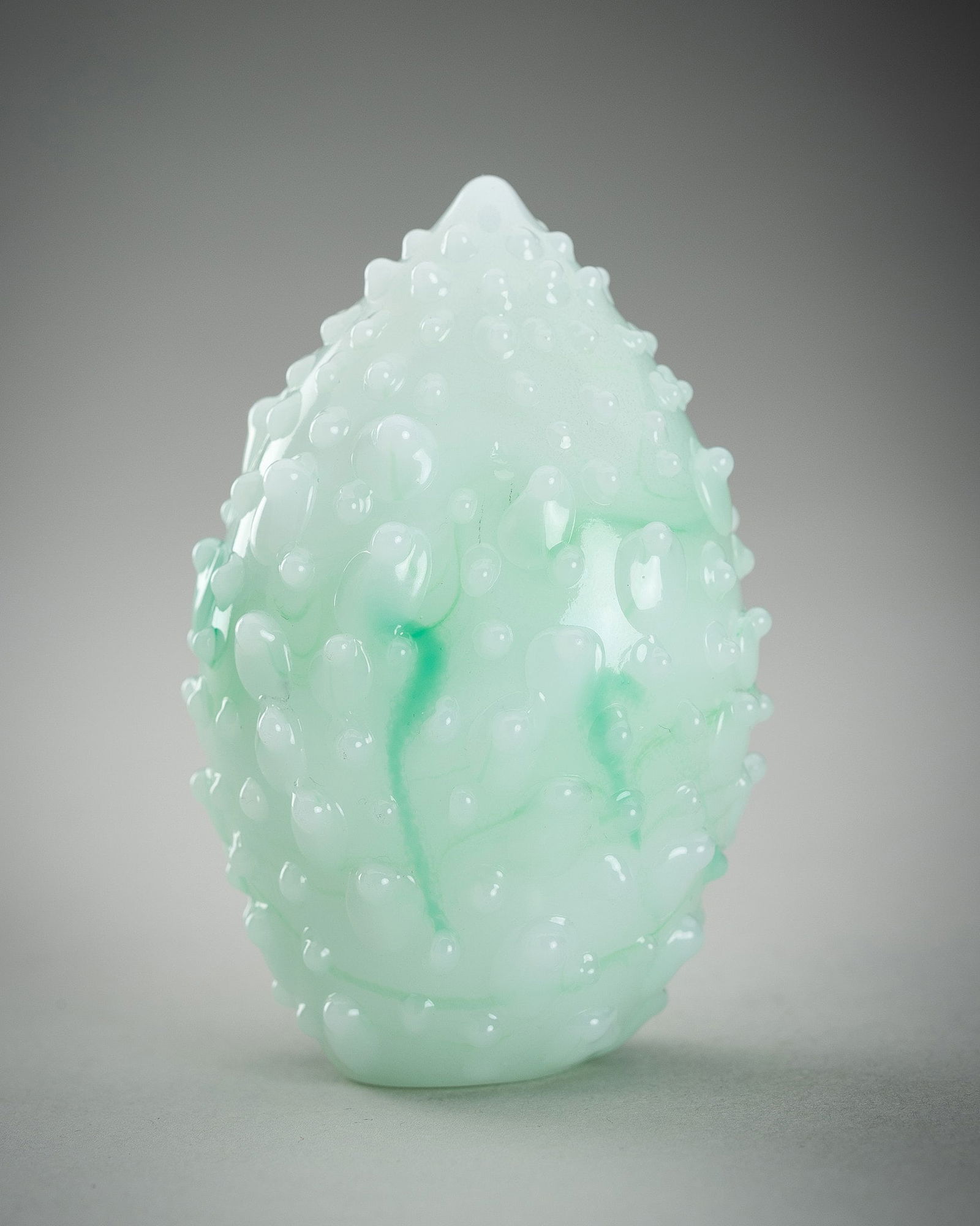 A 'JADEITE IMITATION' GLASS SNUFF BOTTLE IN THE FORM OF A BITTER MELON, c. 1930s: A 'JADEITE IMITATION' GLASS SNUFF BOTTLE IN THE FORM OF A BITTER MELON, c. 1930s China, Republic period (1912-1949). The bright and semi-translucent pale green glass, accented by emerald-green splashe